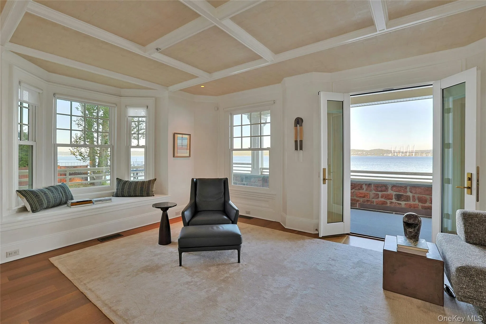 Living area featuring coffered ceiling, wood finished floors, a water view, beam ceiling, and ornamental molding Living area featuring coffered ceiling, wood finished floors, a water view, beam ceiling, and ornamental molding