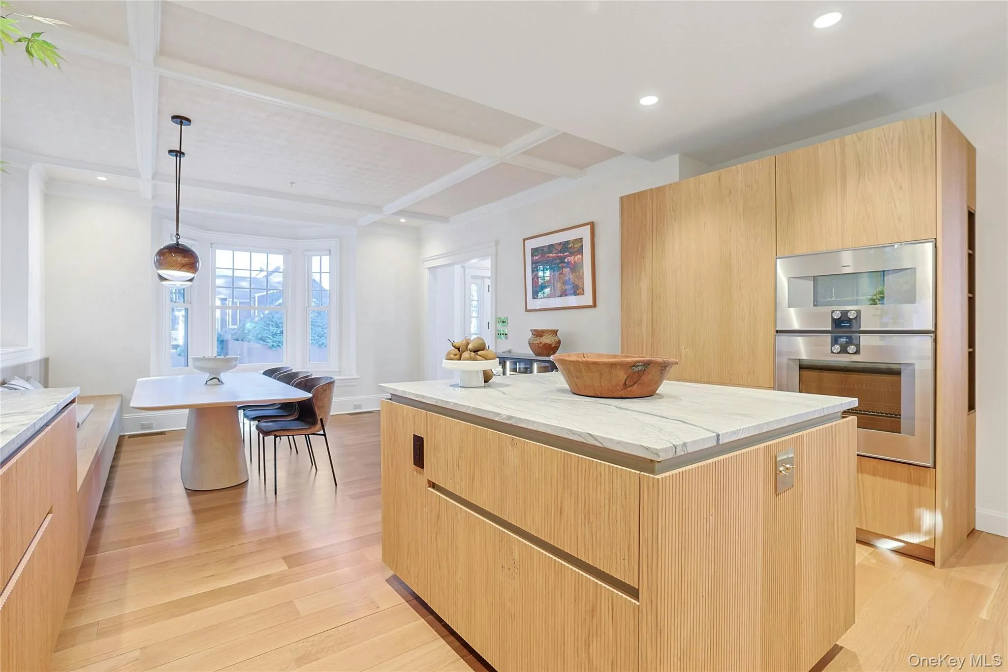 Kitchen featuring modern cabinets, beamed ceiling, light brown cabinetry, pendant lighting, and light wood-style floors Kitchen featuring modern cabinets, beamed ceiling, light brown cabinetry, pendant lighting, and light wood-style floors