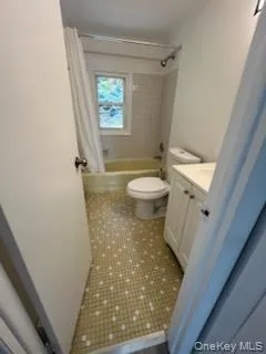 Bathroom with shower / tub combo with curtain, vanity, and dark tile patterned flooring Bathroom with shower / tub combo with curtain, vanity, and dark tile patterned flooring