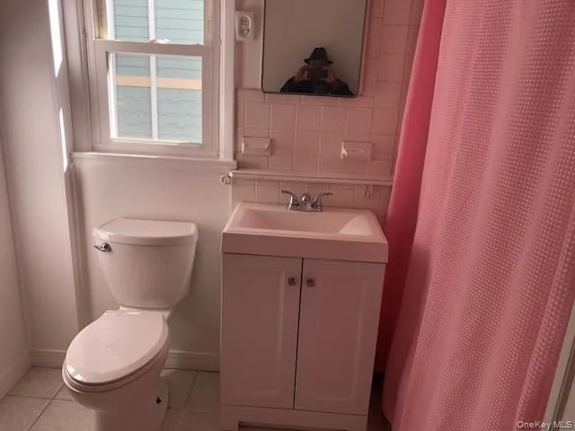 Full bath with a shower with curtain, light tile patterned floors, vanity, and backsplash Full bath with a shower with curtain, light tile patterned floors, vanity, and backsplash