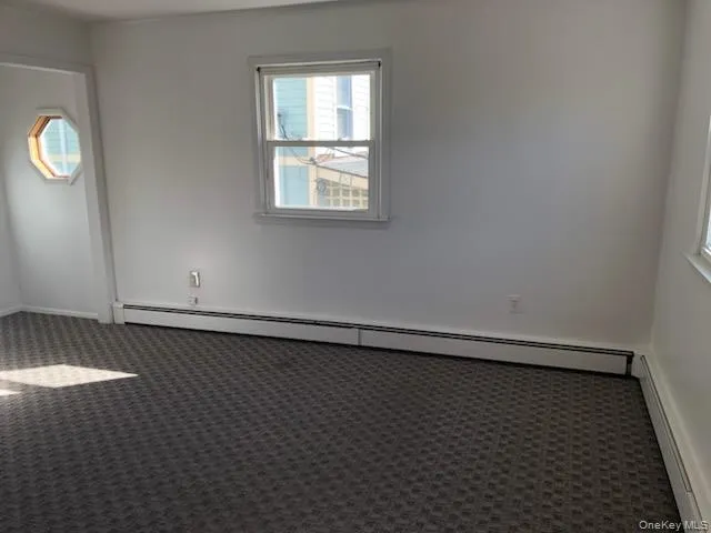 Spare room with dark colored carpet and a baseboard radiator Spare room with dark colored carpet and a baseboard radiator
