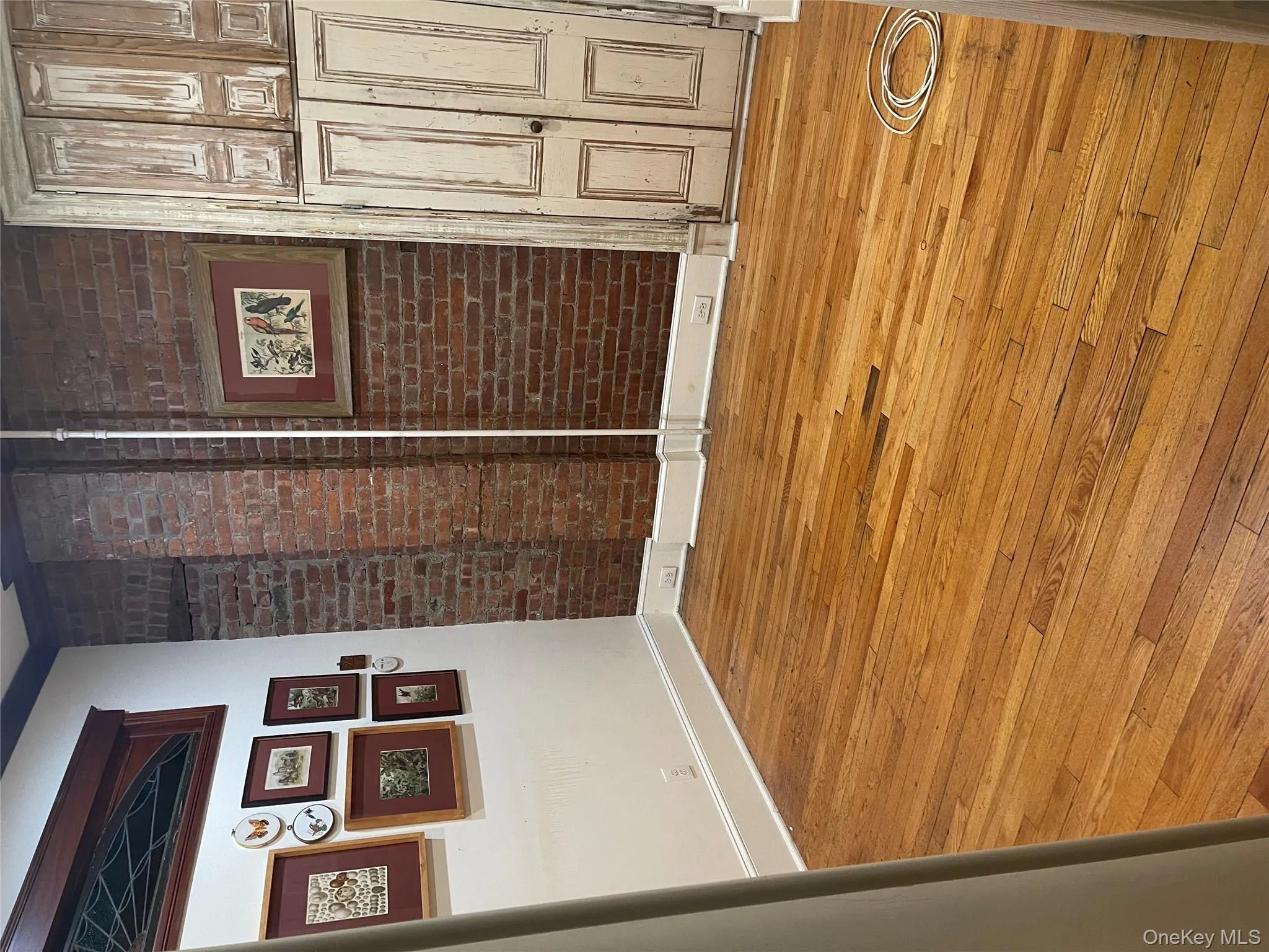 Unfurnished room featuring light wood-style flooring and brick wall Unfurnished room featuring light wood-style flooring and brick wall