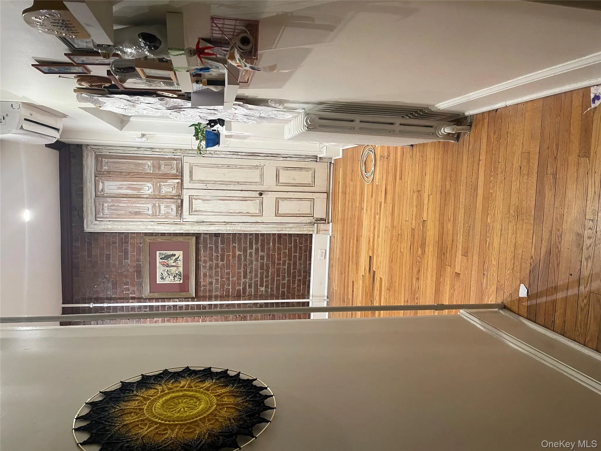 Hallway featuring brick wall, light wood finished floors, radiator heating unit, and a wall mounted air conditioner Hallway featuring brick wall, light wood finished floors, radiator heating unit, and a wall mounted air conditioner