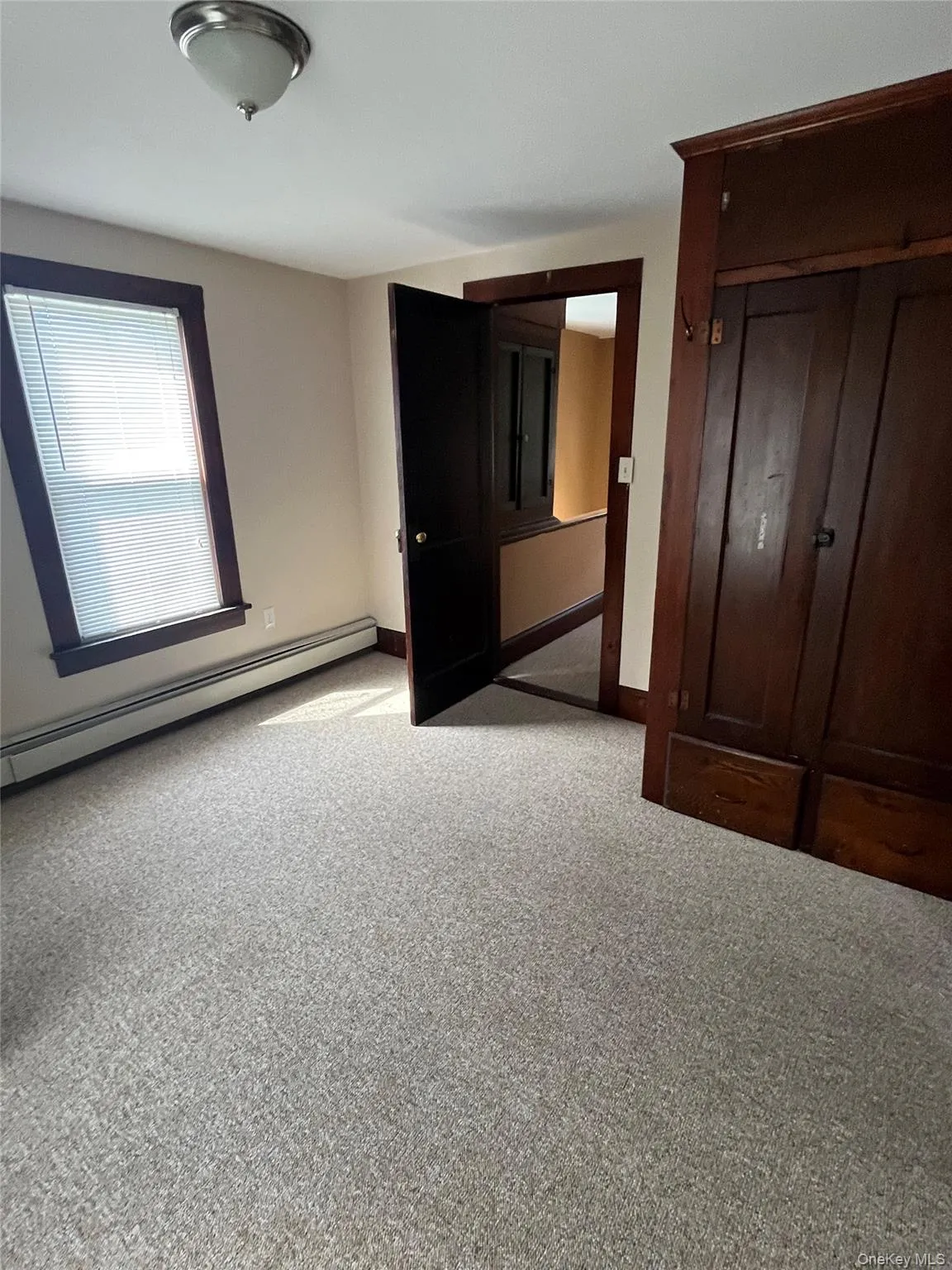 Unfurnished bedroom featuring a baseboard heating unit and light colored carpet Unfurnished bedroom featuring a baseboard heating unit and light colored carpet