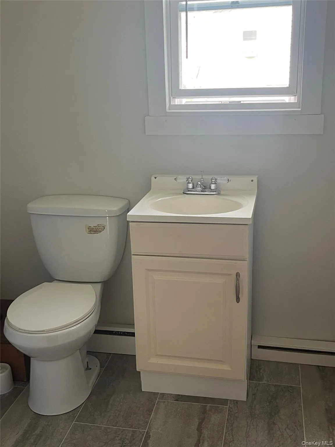 Half bathroom featuring vanity and a baseboard heating unit Half bathroom featuring vanity and a baseboard heating unit