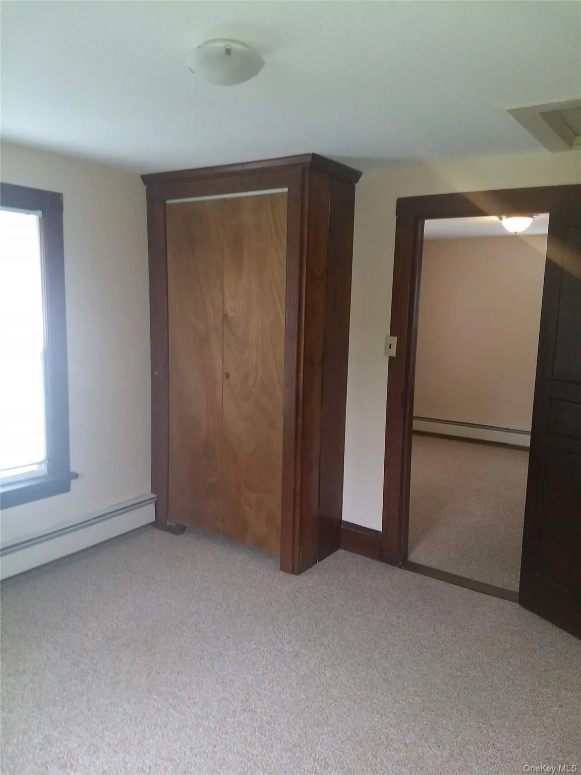 Unfurnished bedroom featuring a baseboard heating unit, light colored carpet, and a baseboard radiator Unfurnished bedroom featuring a baseboard heating unit, light colored carpet, and a baseboard radiator