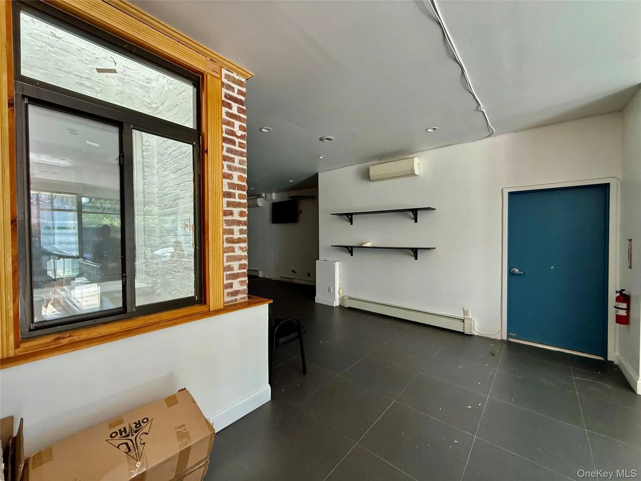 Unfurnished living room featuring a baseboard heating unit, dark tile patterned flooring, an AC wall unit, and recessed lighting Unfurnished living room featuring a baseboard heating unit, dark tile patterned flooring, an AC wall unit, and recessed lighting