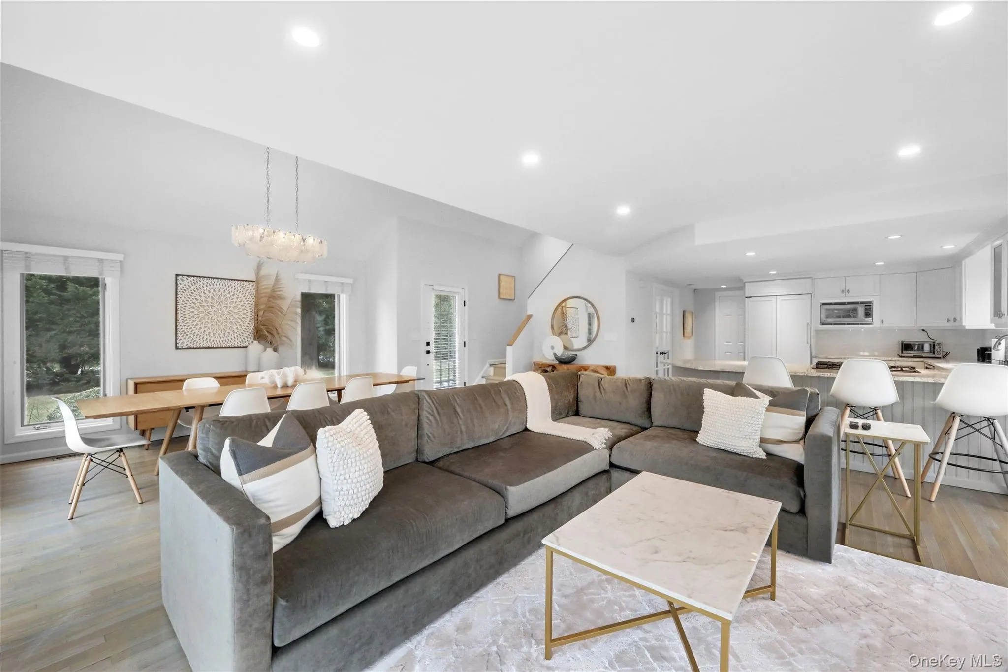 Living room with light wood-style floors, recessed lighting, a chandelier, and stairs Living room with light wood-style floors, recessed lighting, a chandelier, and stairs