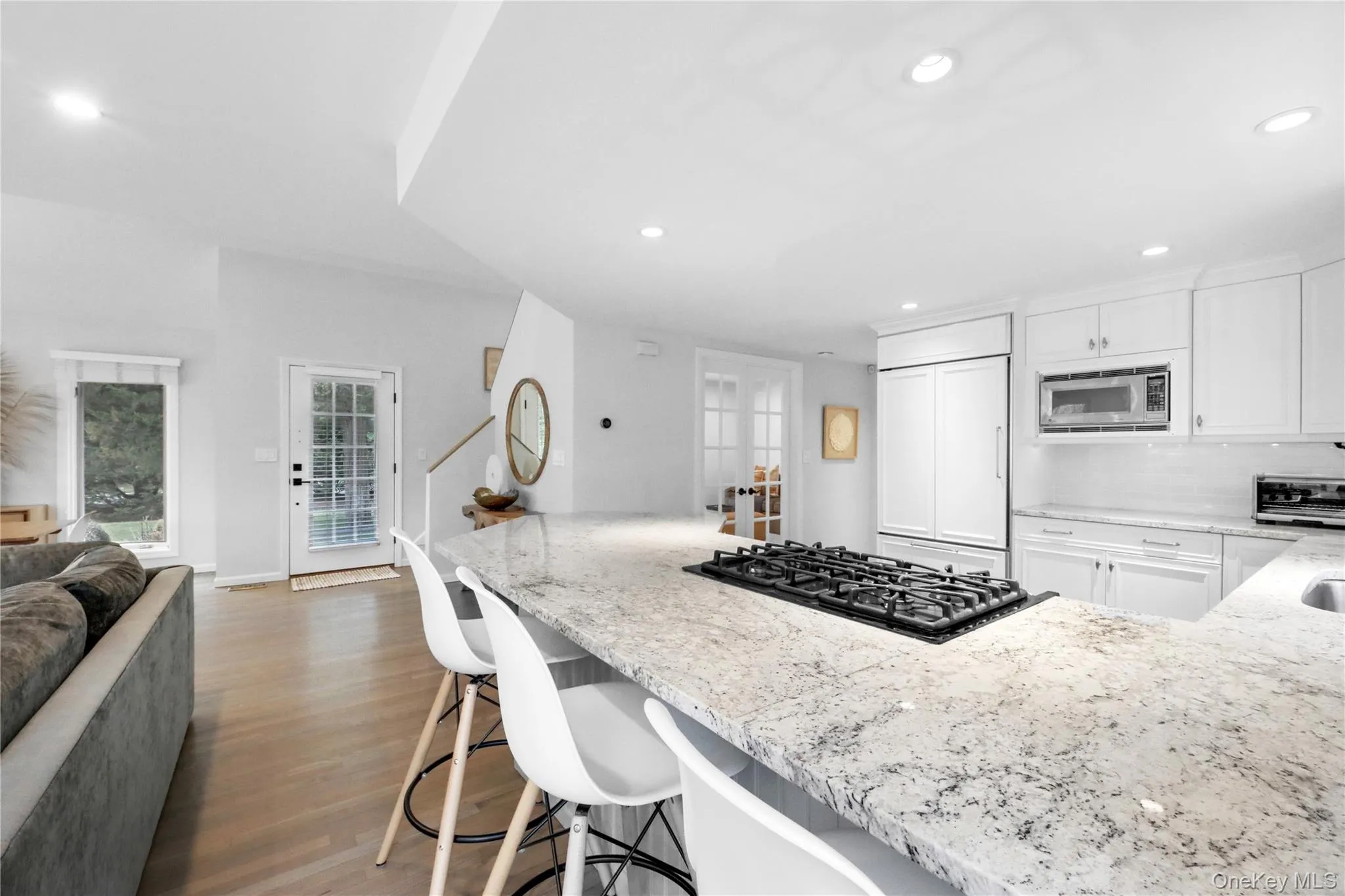 Kitchen featuring light stone countertops, open floor plan, white cabinets, built in appliances, and dark wood-type flooring Kitchen featuring light stone countertops, open floor plan, white cabinets, built in appliances, and dark wood-type flooring
