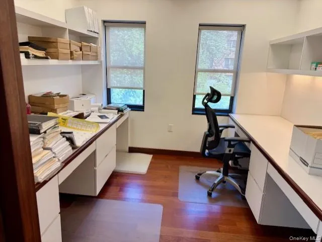 Home office with built in study area, plenty of natural light, and dark wood-style flooring Home office with built in study area, plenty of natural light, and dark wood-style flooring