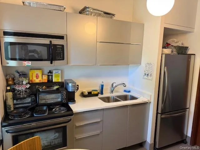 Kitchen with gray cabinets, appliances with stainless steel finishes, light countertops, and modern cabinets Kitchen with gray cabinets, appliances with stainless steel finishes, light countertops, and modern cabinets