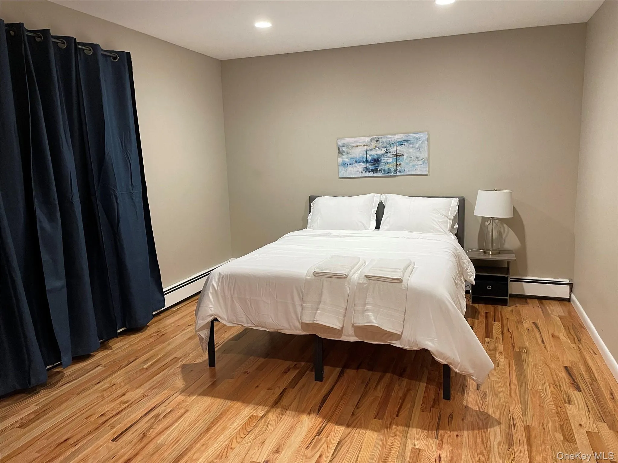 Bedroom featuring light wood-style floors, a baseboard heating unit, and recessed lighting Bedroom featuring light wood-style floors, a baseboard heating unit, and recessed lighting