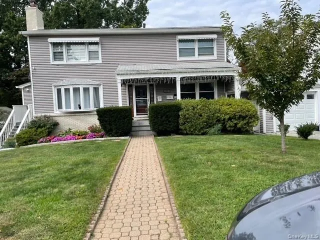 View of front facade featuring a front lawn, brick siding, a chimney, and covered porch View of front facade featuring a front lawn, brick siding, a chimney, and covered porch