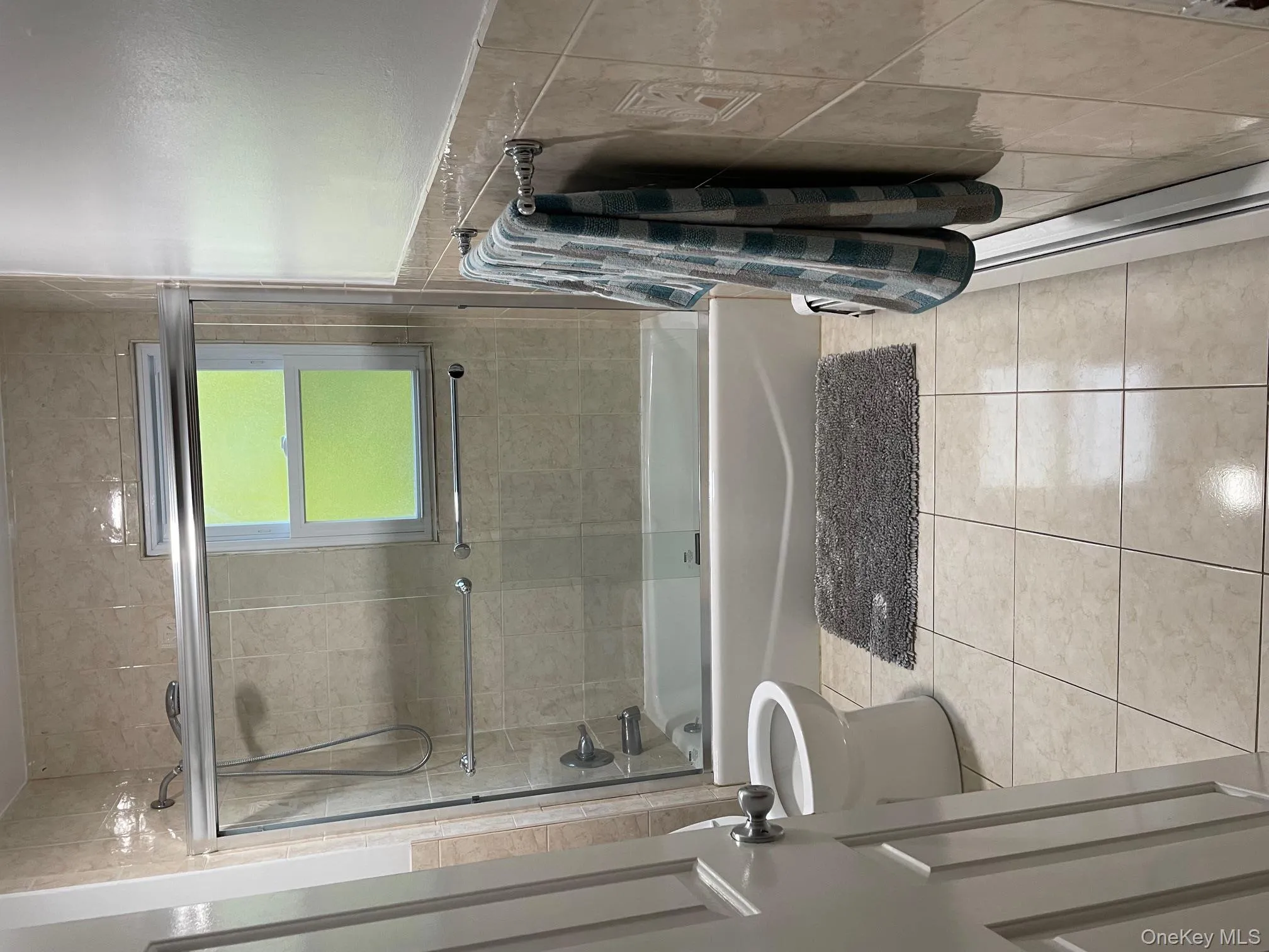 Full bath with enclosed tub / shower combo, tile patterned flooring, and tile walls Full bath with enclosed tub / shower combo, tile patterned flooring, and tile walls