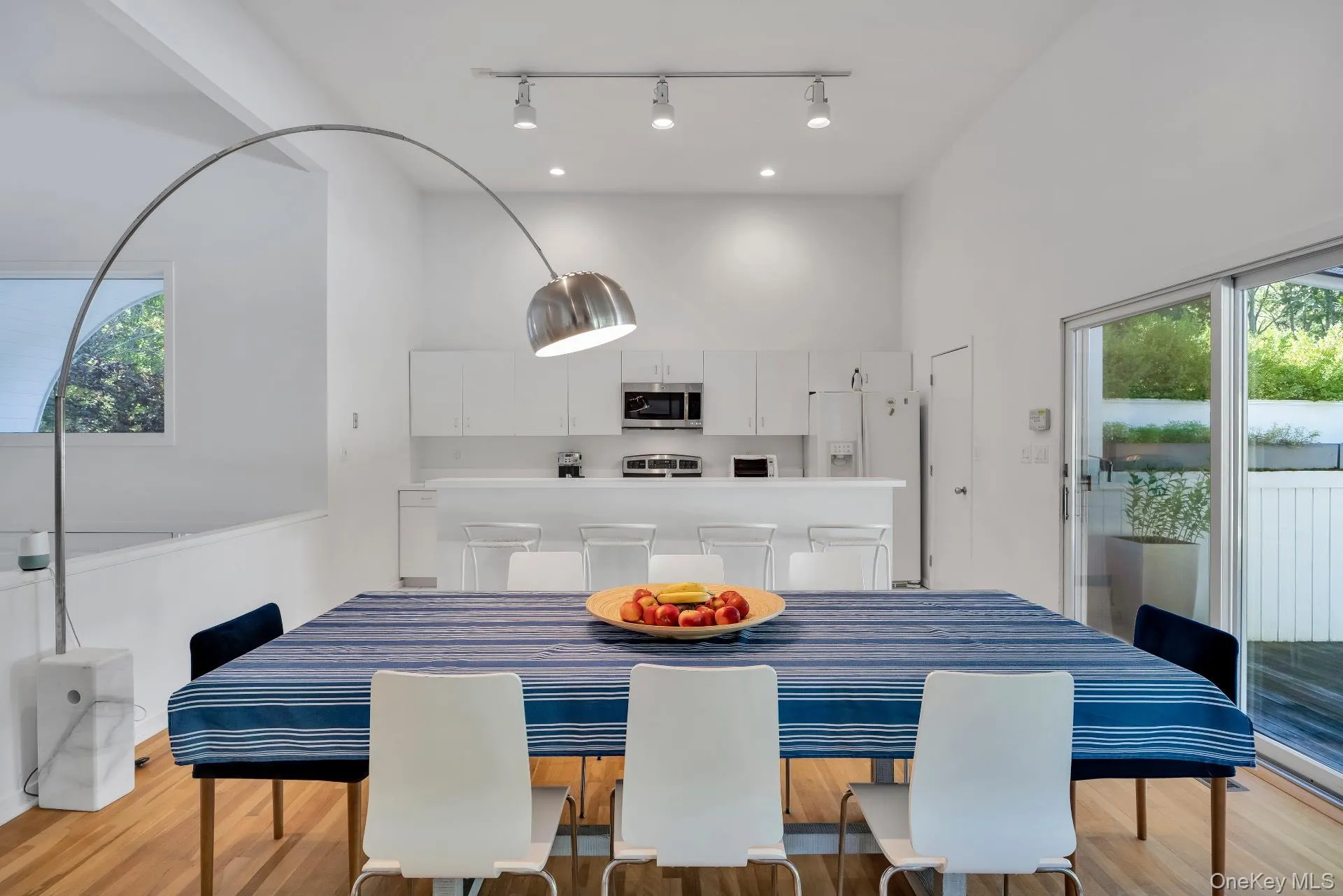 Dining area featuring healthy amount of natural light, light wood-style floors, a towering ceiling, and track lighting Dining area featuring healthy amount of natural light, light wood-style floors, a towering ceiling, and track lighting
