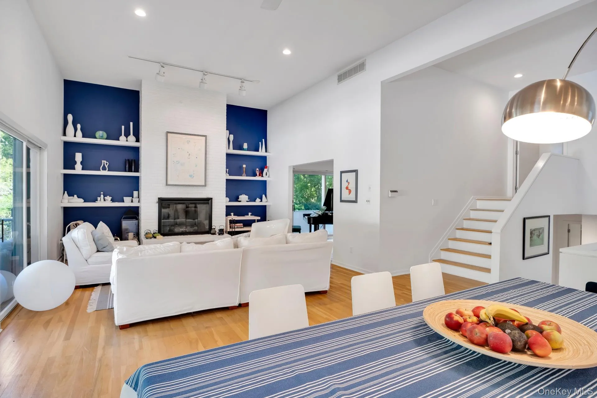 Dining space featuring built in shelves, light wood finished floors, a fireplace, stairs, and recessed lighting Dining space featuring built in shelves, light wood finished floors, a fireplace, stairs, and recessed lighting