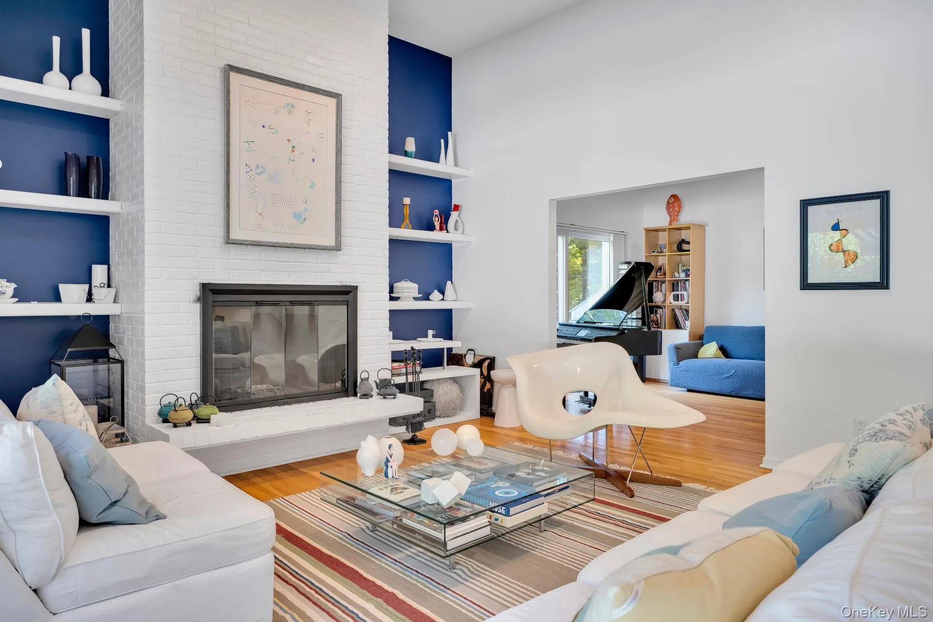 Living room featuring wood finished floors, built in shelves, a fireplace, and a towering ceiling Living room featuring wood finished floors, built in shelves, a fireplace, and a towering ceiling