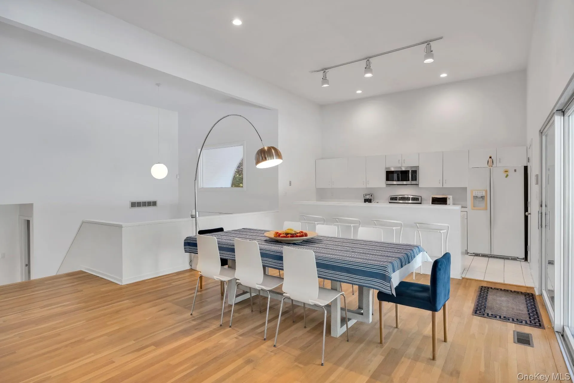 Dining space featuring track lighting, light wood finished floors, and a high ceiling Dining space featuring track lighting, light wood finished floors, and a high ceiling
