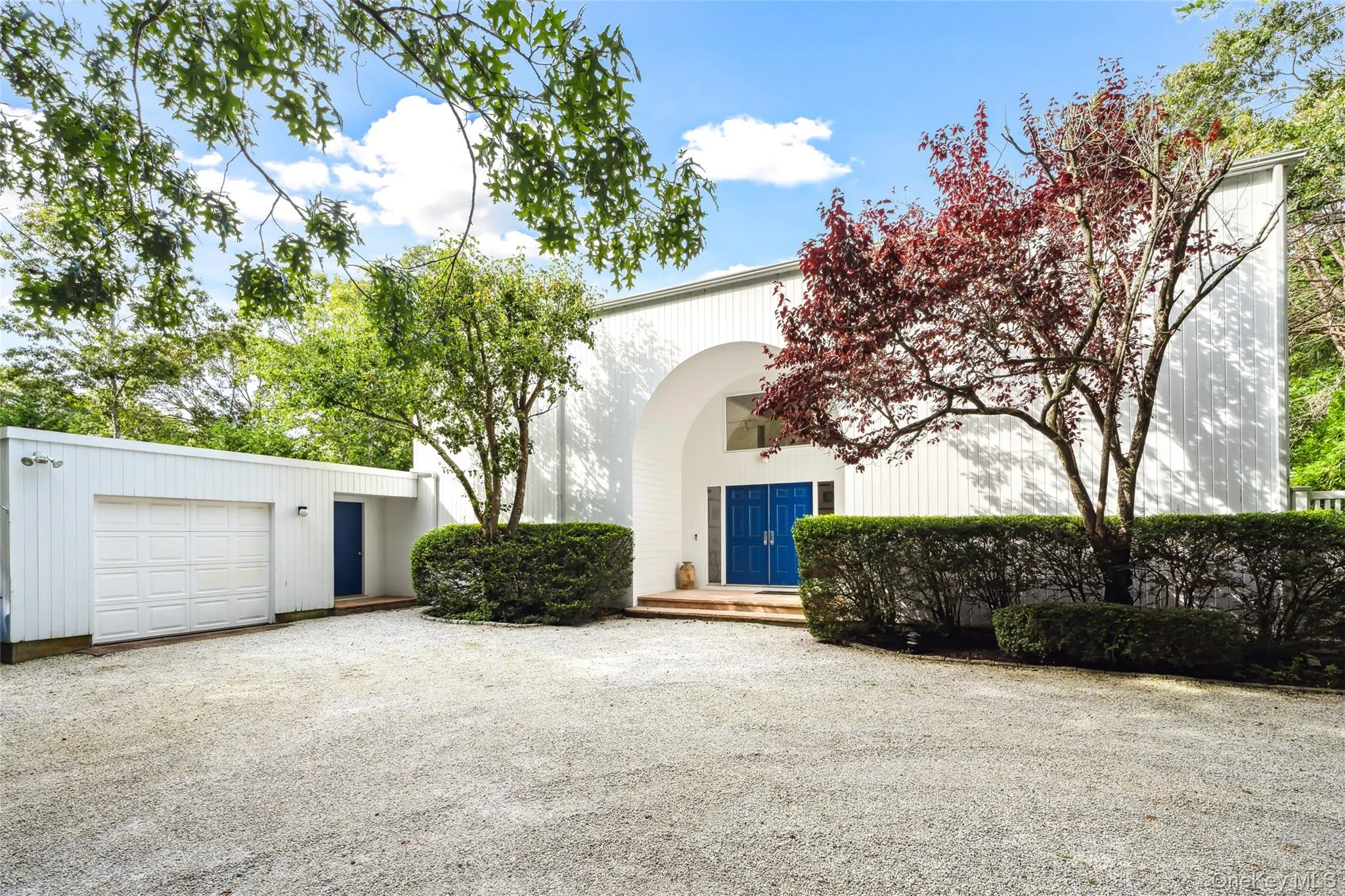 View of front facade with gravel driveway, a wooden deck, and an attached garage View of front facade with gravel driveway, a wooden deck, and an attached garage