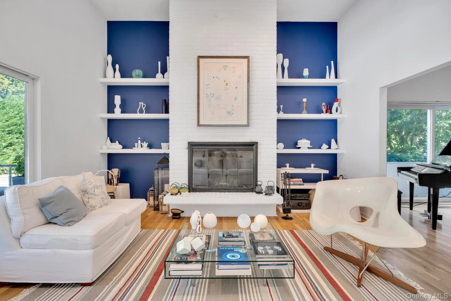 Living room with wood finished floors, built in features, a brick fireplace, and a towering ceiling Living room with wood finished floors, built in features, a brick fireplace, and a towering ceiling
