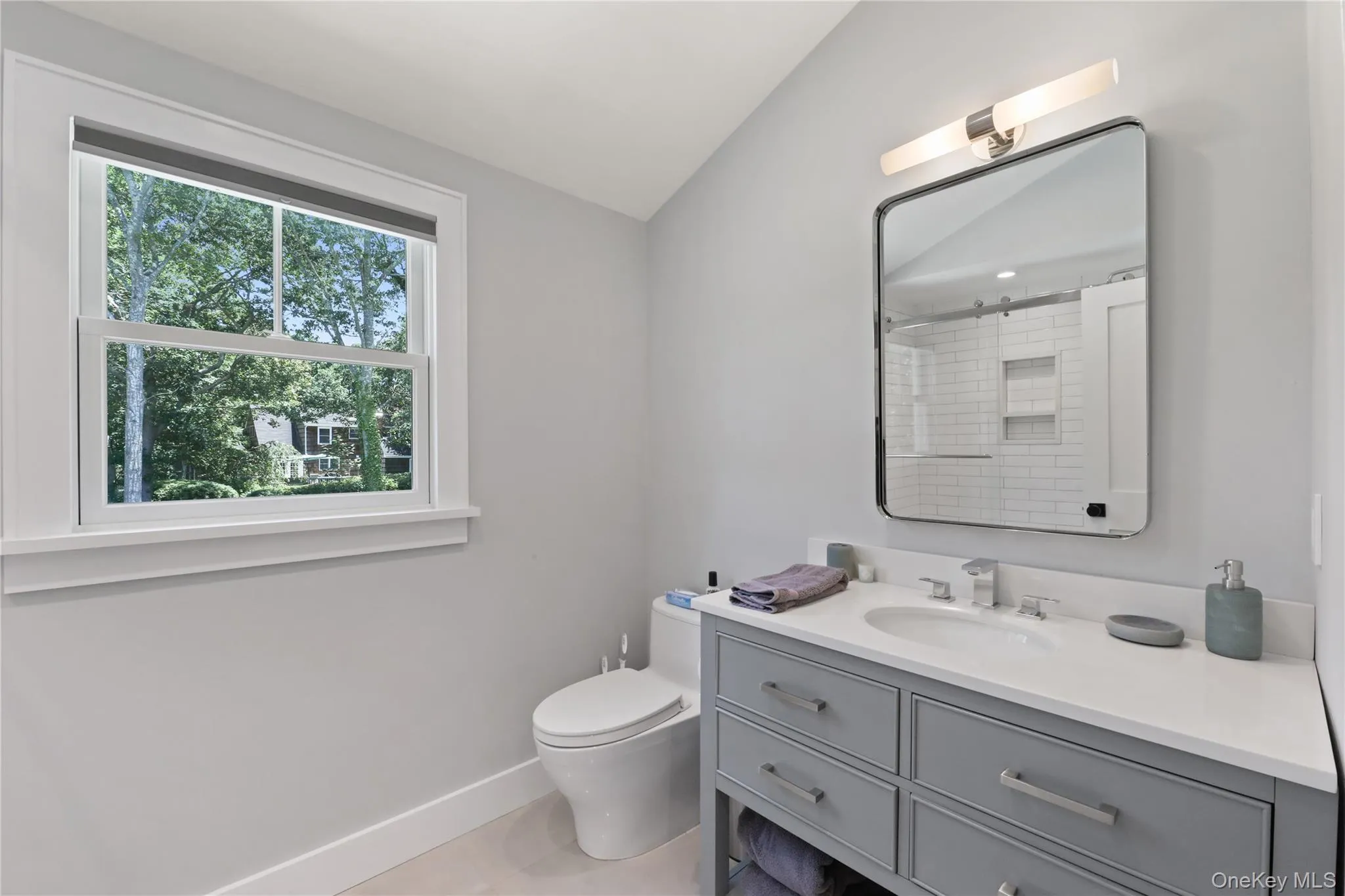 Bathroom featuring vanity, lofted ceiling, a shower with shower curtain, and light tile patterned floors Bathroom featuring vanity, lofted ceiling, a shower with shower curtain, and light tile patterned floors