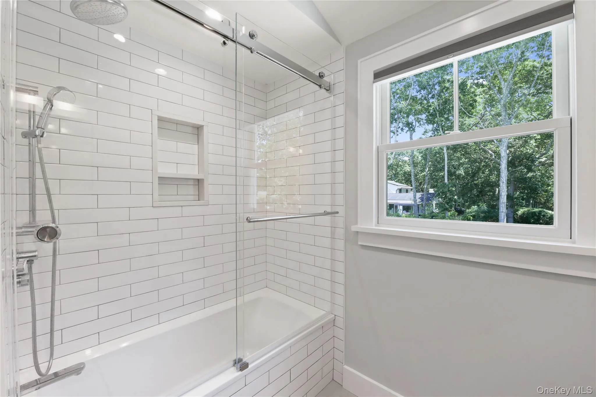Full bathroom featuring a combined bath / shower with rainfall shower and baseboards Full bathroom featuring a combined bath / shower with rainfall shower and baseboards
