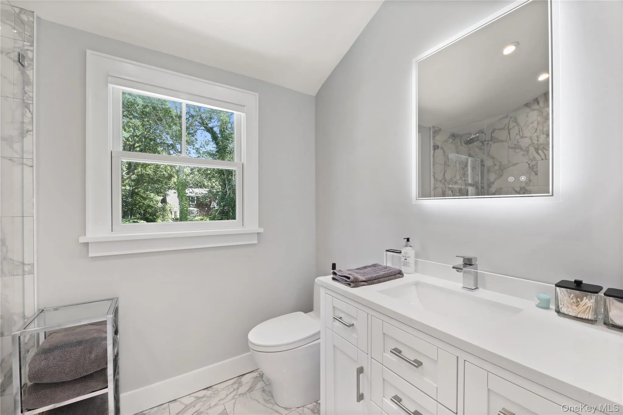 Full bath with light marble finish floors, vanity, and a marble finish shower Full bath with light marble finish floors, vanity, and a marble finish shower