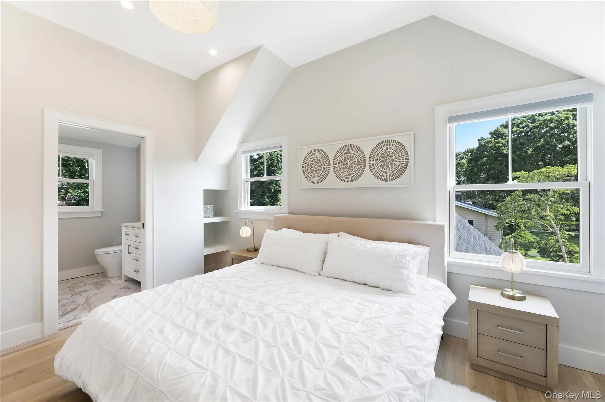 Bedroom with light wood finished floors, vaulted ceiling, recessed lighting, and ensuite bath Bedroom with light wood finished floors, vaulted ceiling, recessed lighting, and ensuite bath