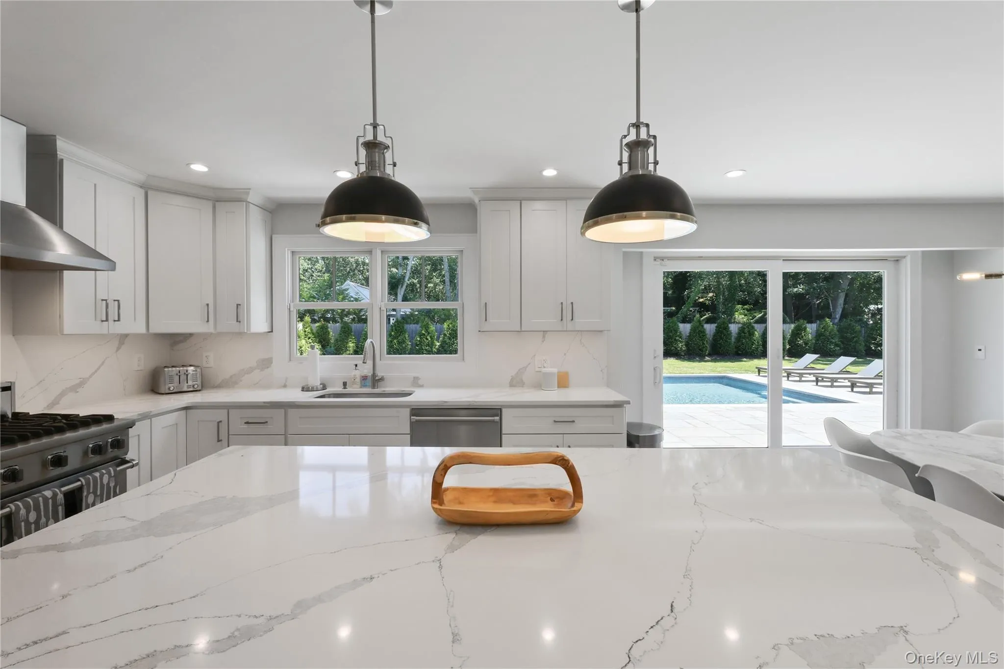 Kitchen featuring light stone countertops, white cabinetry, backsplash, pendant lighting, and recessed lighting Kitchen featuring light stone countertops, white cabinetry, backsplash, pendant lighting, and recessed lighting