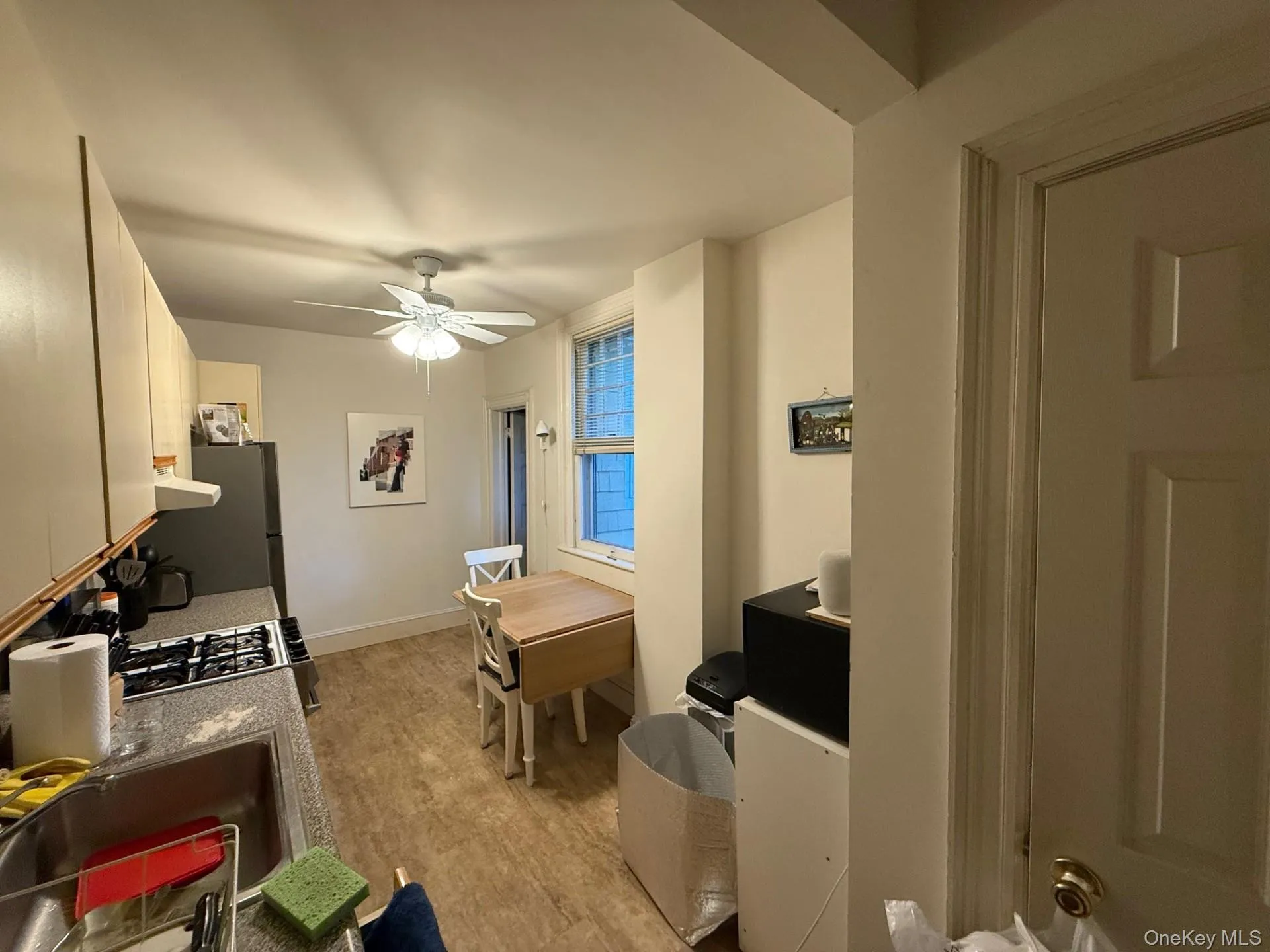 Kitchen with light wood finished floors, white cabinets, a ceiling fan, freestanding refrigerator, and range with gas cooktop Kitchen with light wood finished floors, white cabinets, a ceiling fan, freestanding refrigerator, and range with gas cooktop