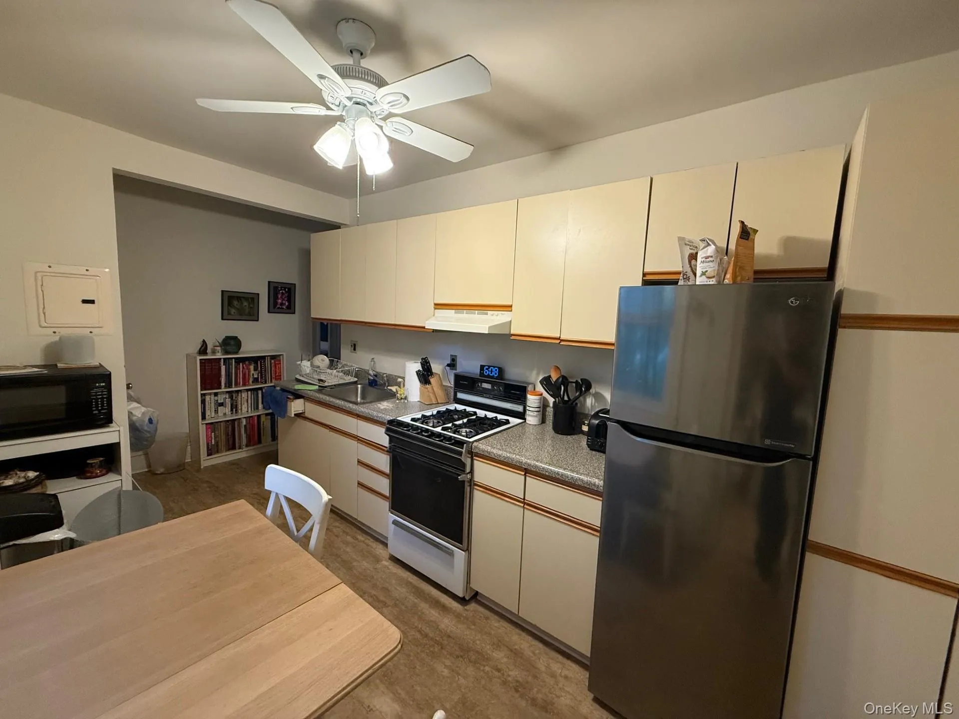 Kitchen with freestanding refrigerator, gas range gas stove, black microwave, a ceiling fan, and under cabinet range hood Kitchen with freestanding refrigerator, gas range gas stove, black microwave, a ceiling fan, and under cabinet range hood