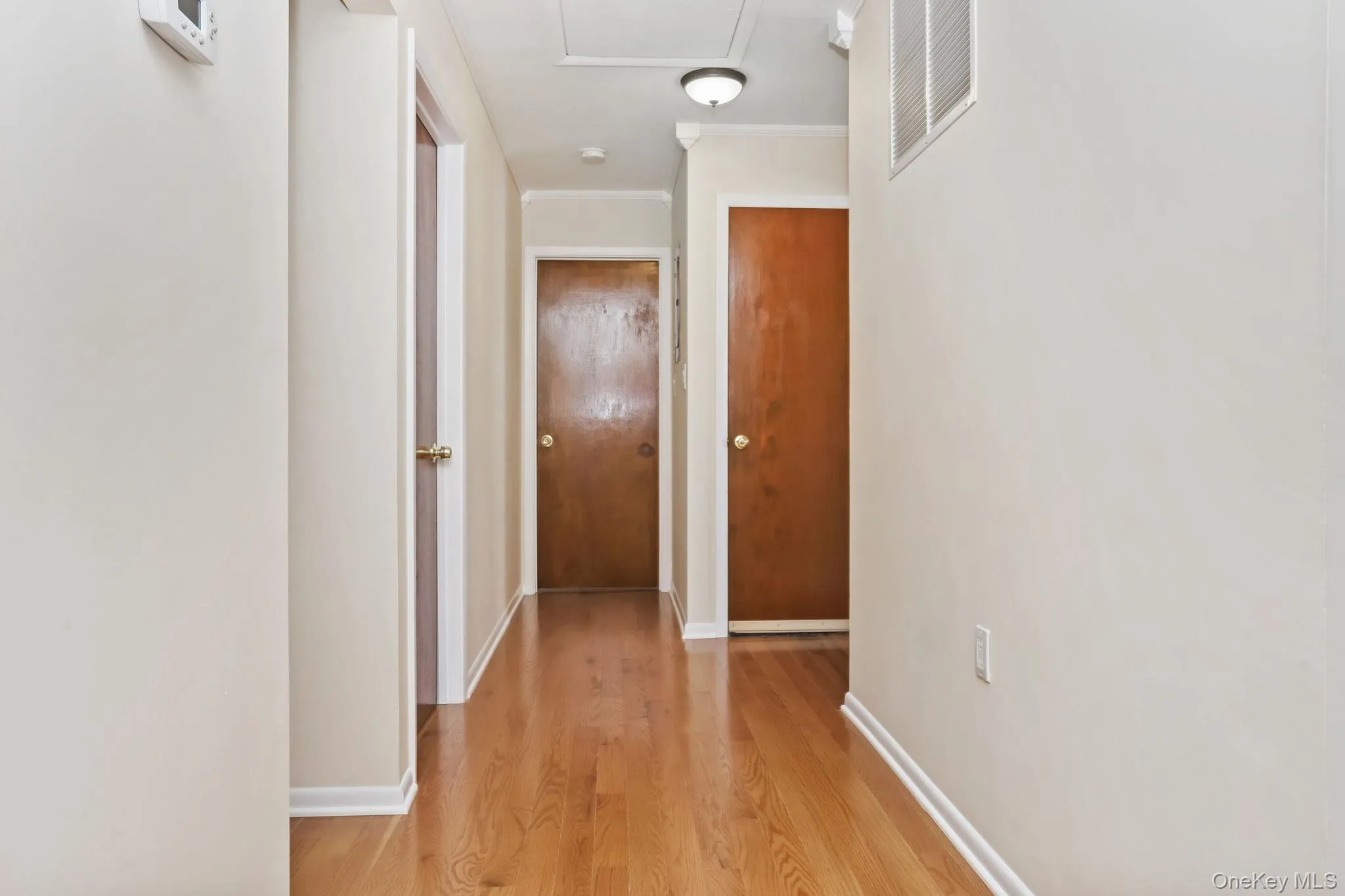 Hall with light wood-style flooring and molding Hall with light wood-style flooring and molding