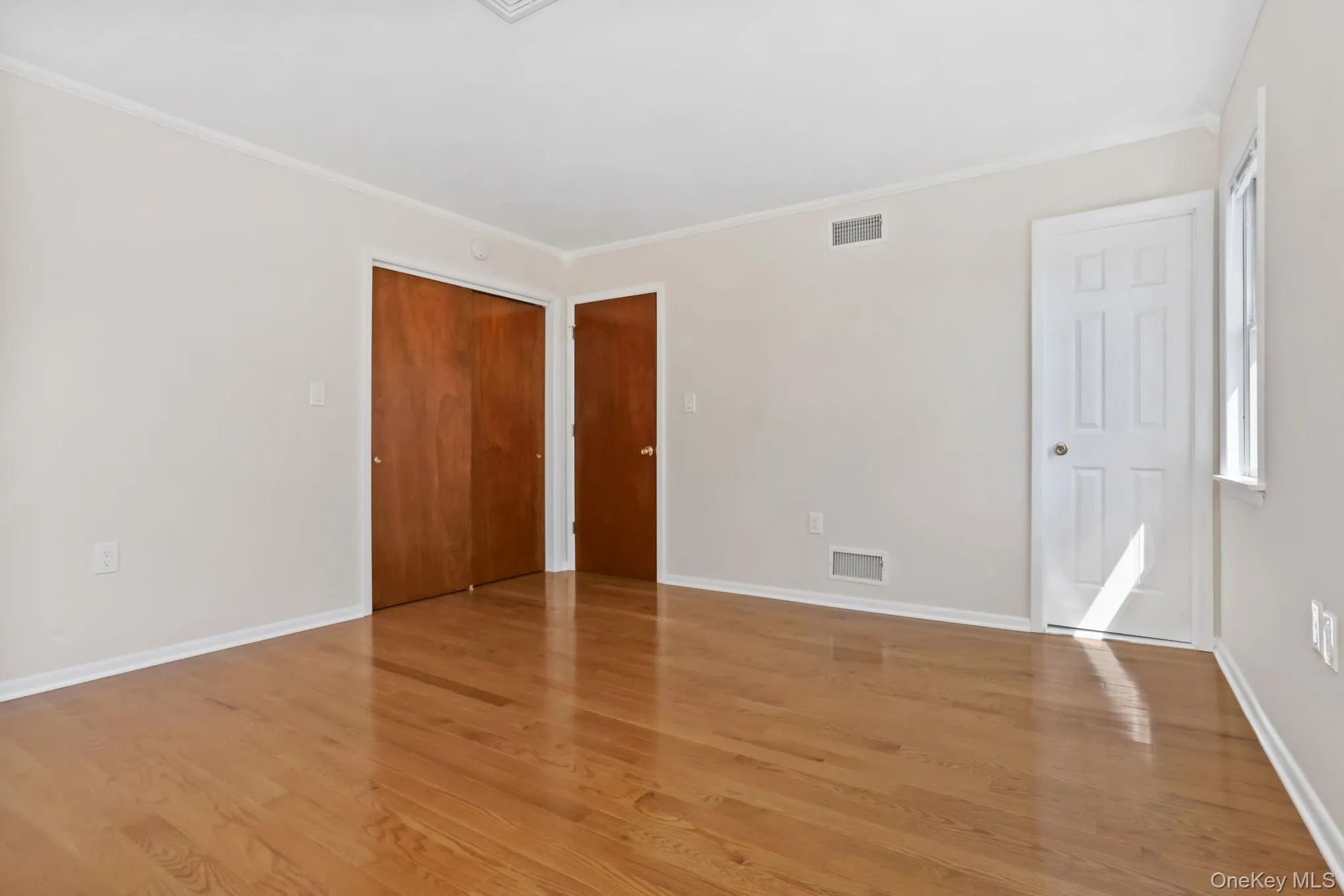 Primary bedroom featuring crown molding, light wood finished floors, and a closet and en suite Primary bedroom featuring crown molding, light wood finished floors, and a closet and en suite