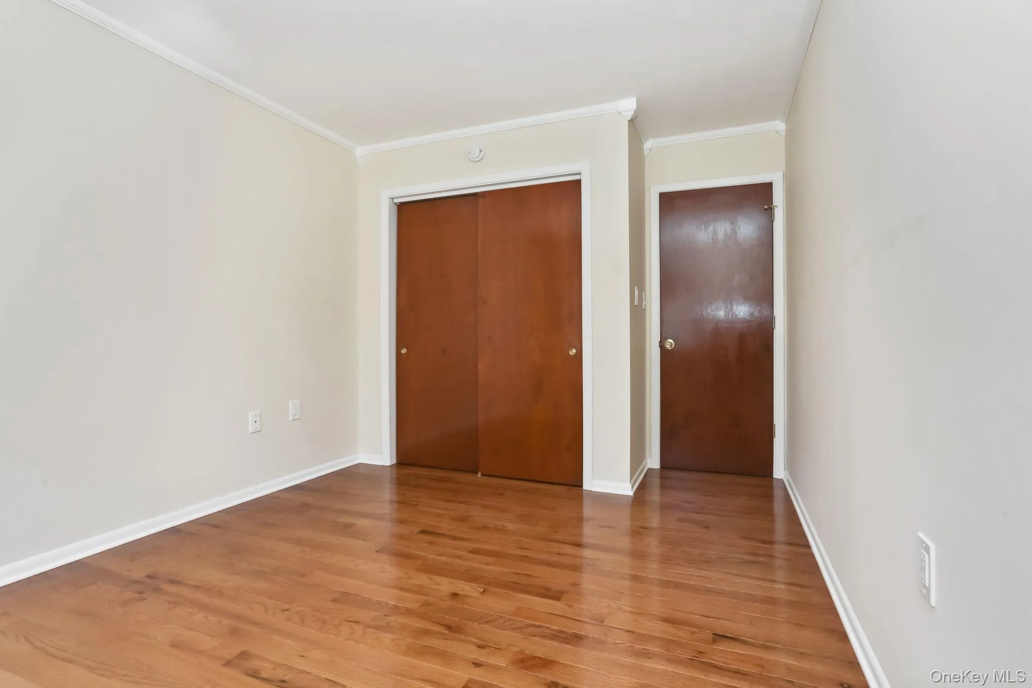 Bedroom 2 featuring molding, wood finished floors, and a closet Bedroom 2 featuring molding, wood finished floors, and a closet