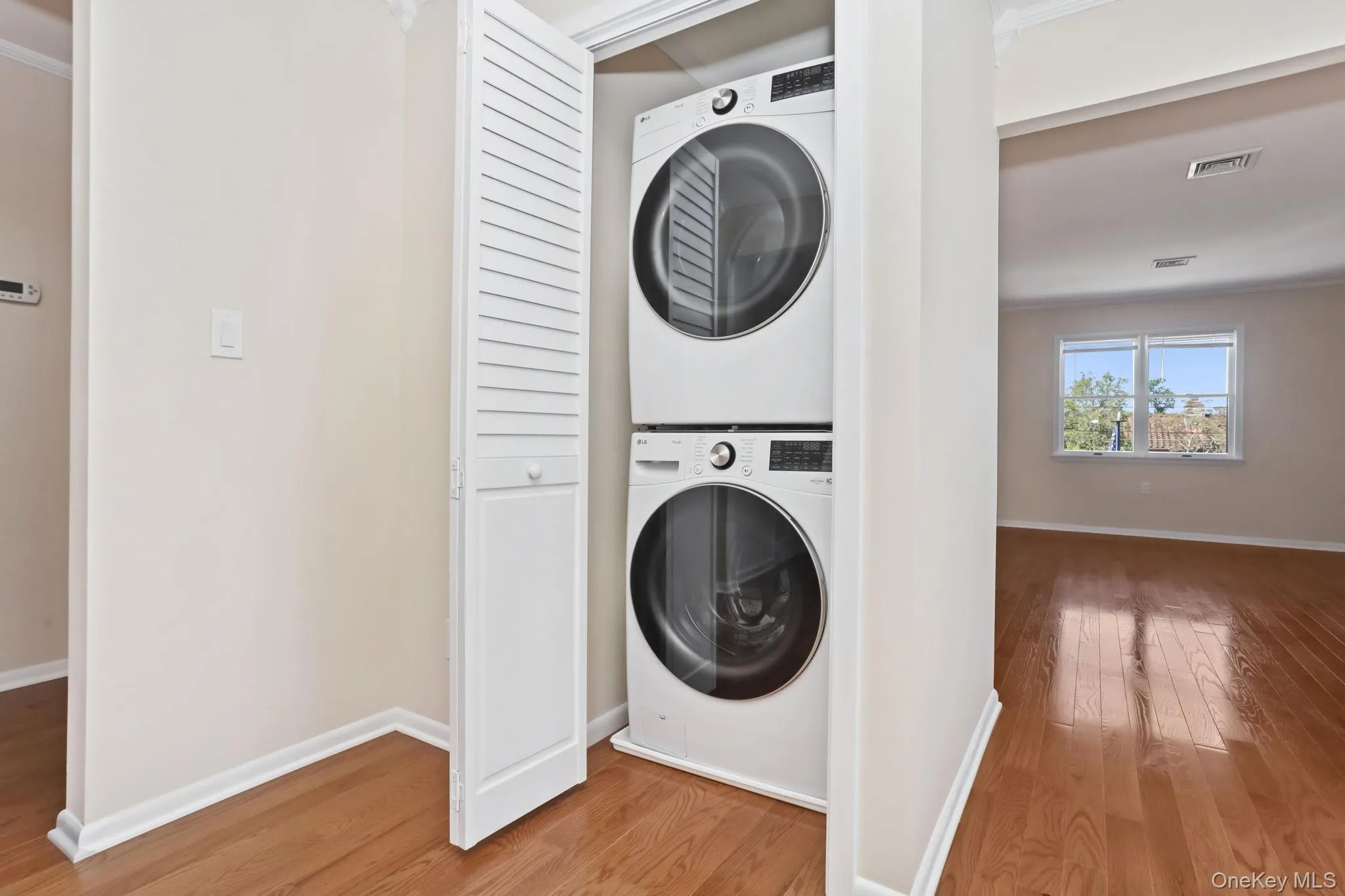 Laundry area with stacked washing machine and dryer, light wood-type flooring. Laundry area with stacked washing machine and dryer, light wood-type flooring.