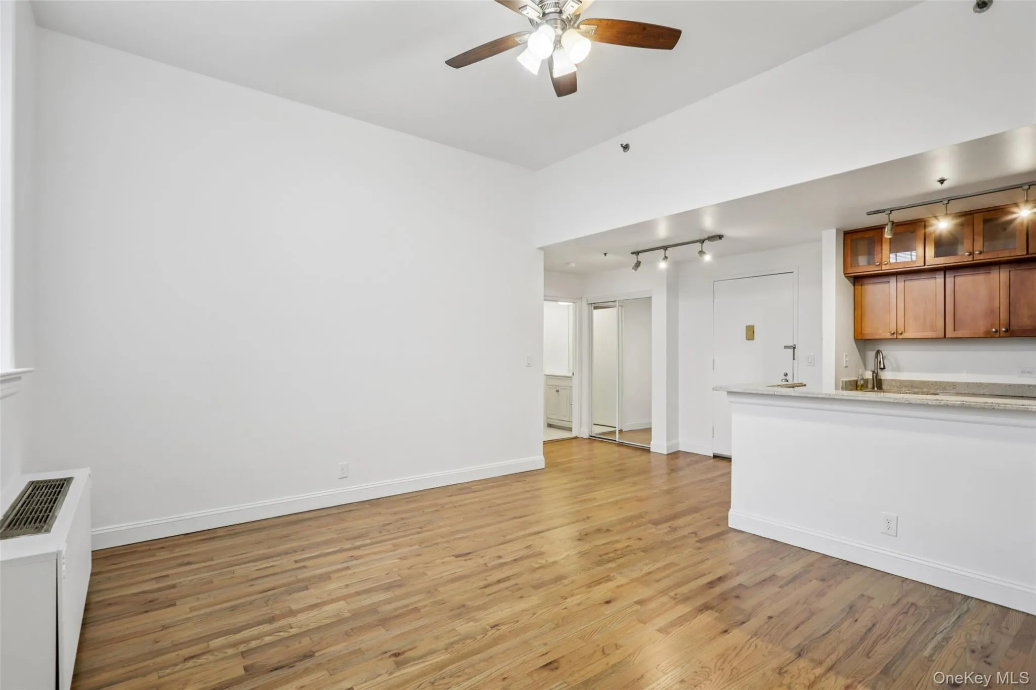 Unfurnished living room with light wood finished floors, ceiling fan, and radiator Unfurnished living room with light wood finished floors, ceiling fan, and radiator