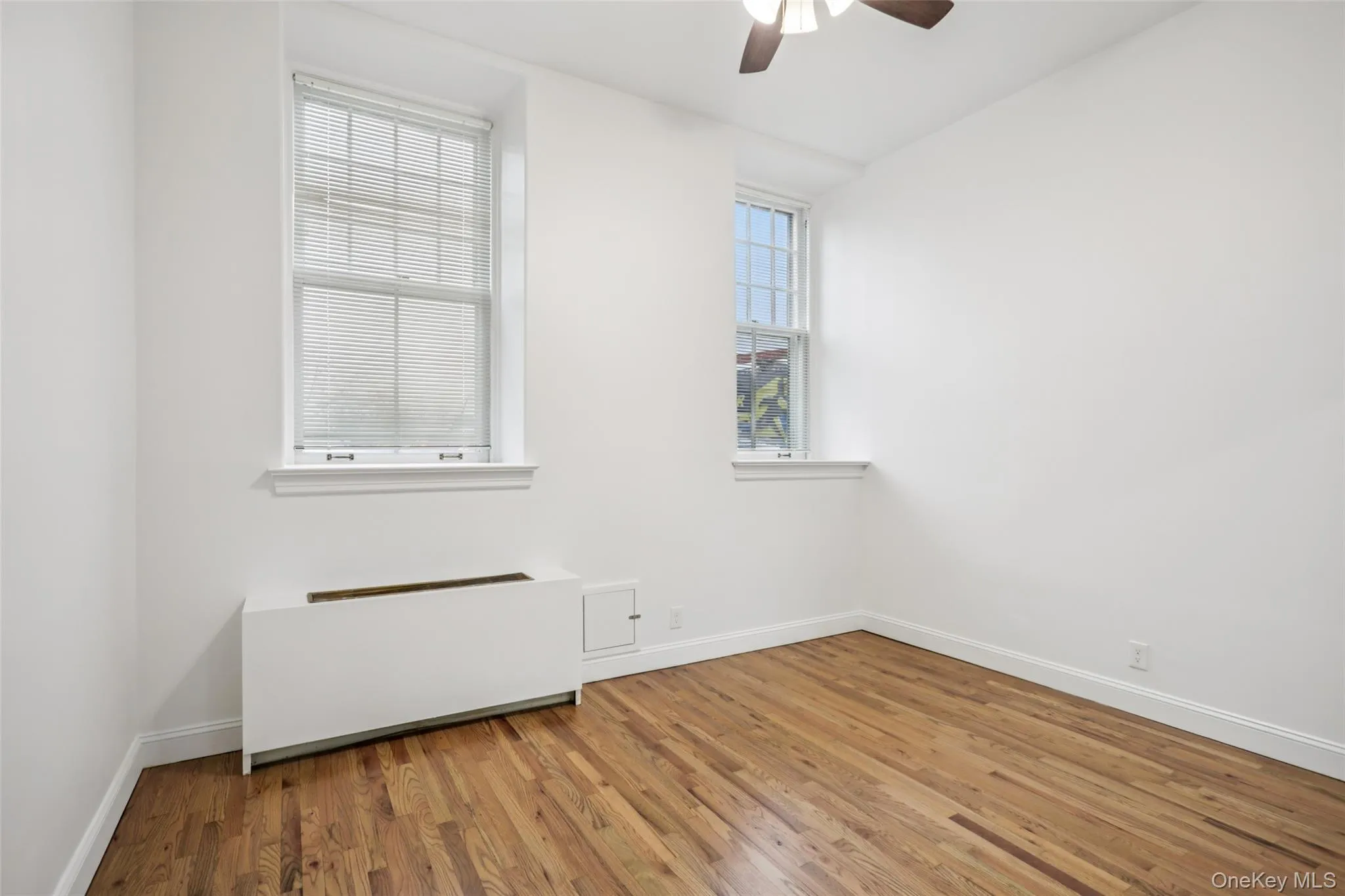 Spare room featuring radiator, wood finished floors, and a ceiling fan Spare room featuring radiator, wood finished floors, and a ceiling fan