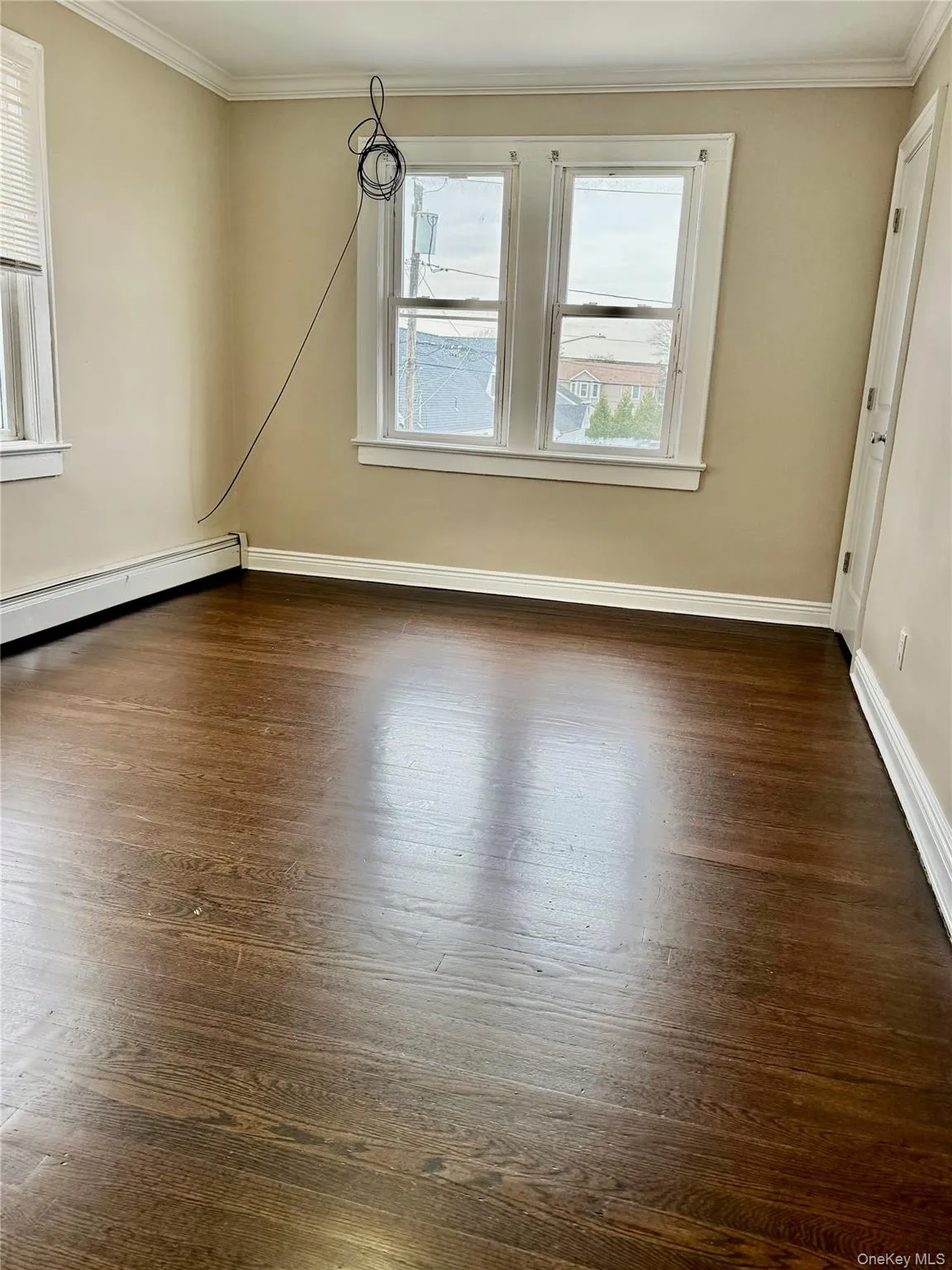 Unfurnished room featuring crown molding, a baseboard heating unit, and dark wood finished floors Unfurnished room featuring crown molding, a baseboard heating unit, and dark wood finished floors