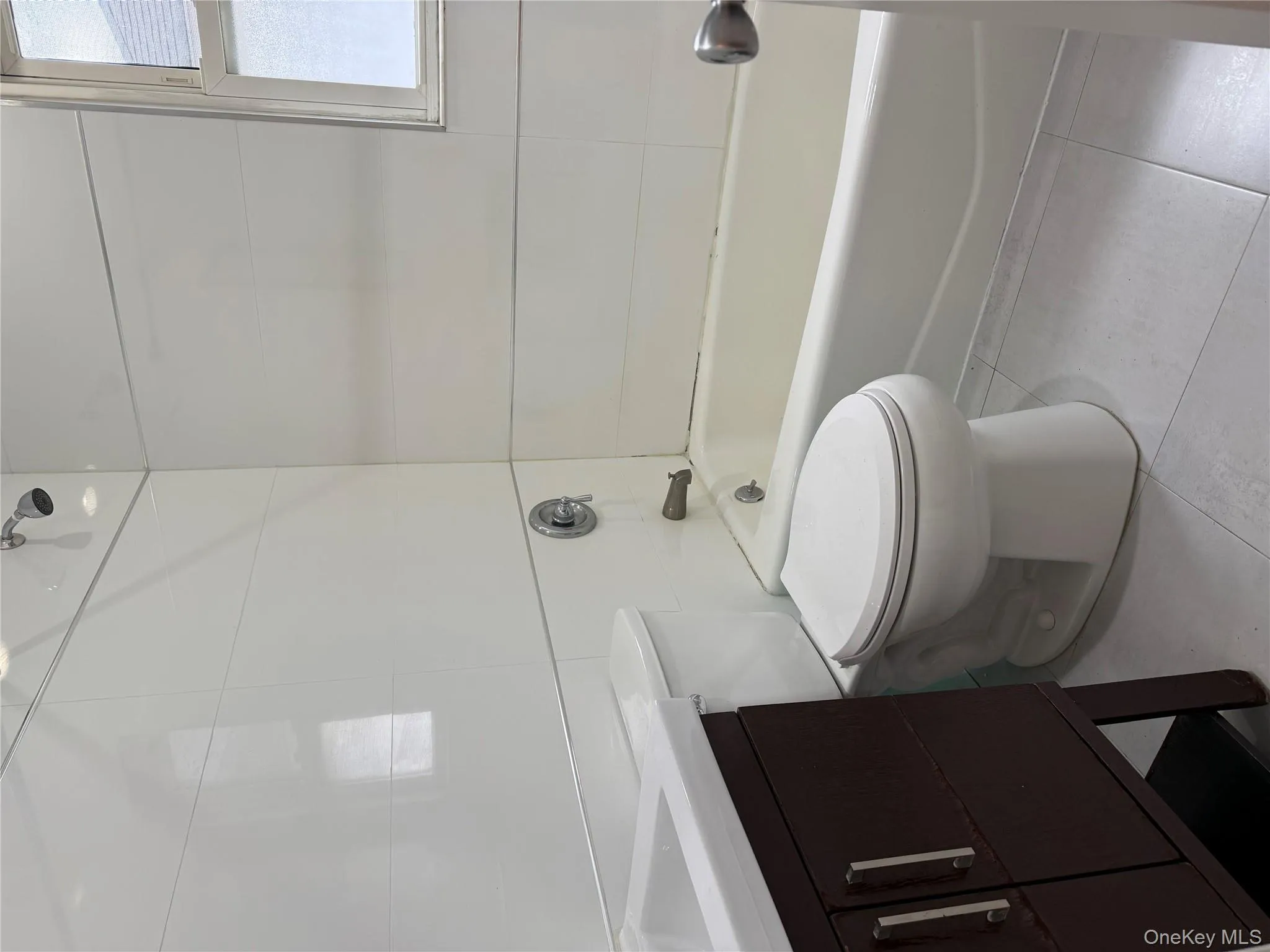 Bathroom featuring vanity, tile walls, light tile patterned flooring, and tub / shower combination Bathroom featuring vanity, tile walls, light tile patterned flooring, and tub / shower combination