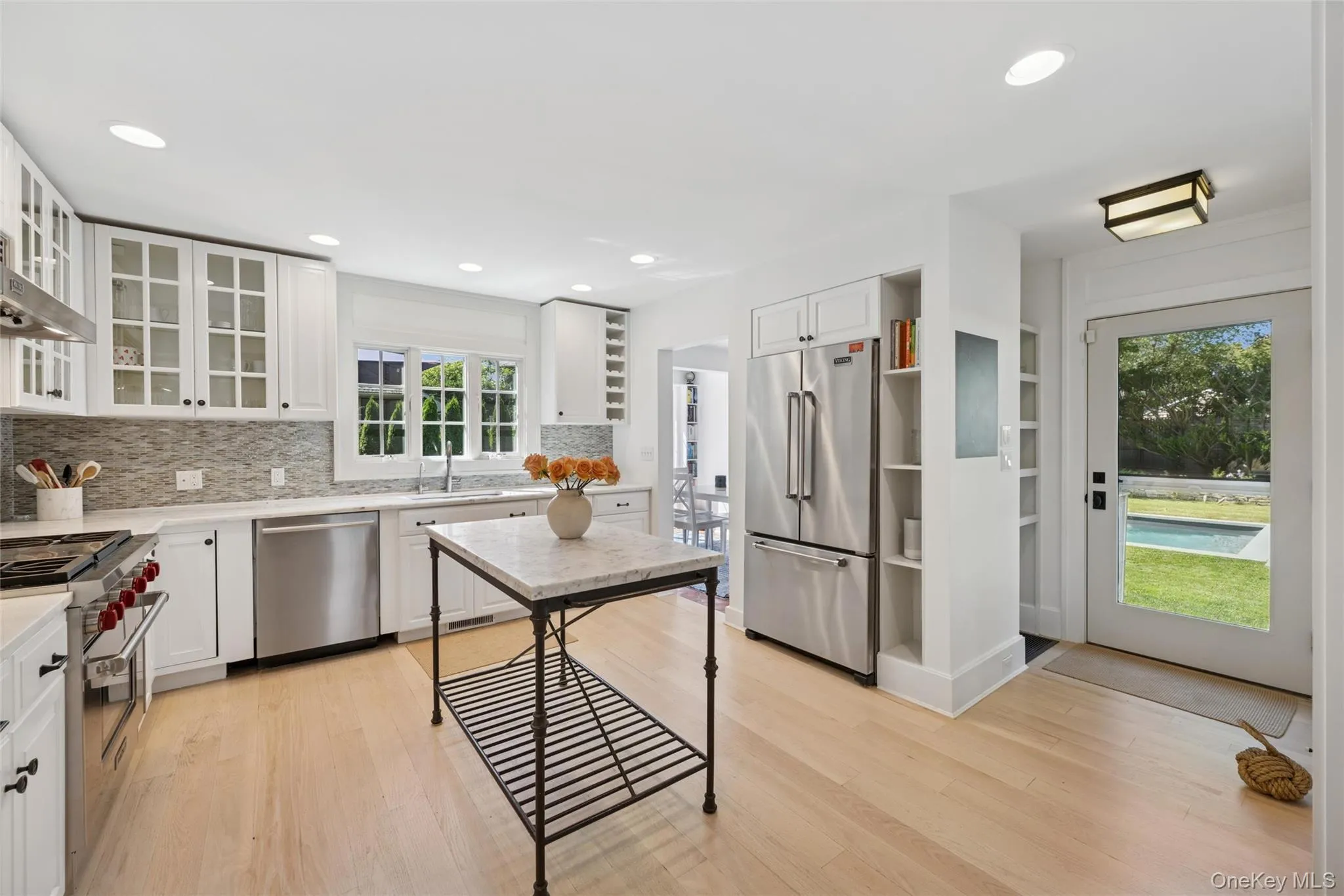 Kitchen featuring premium appliances, recessed lighting, white cabinetry, light wood-style flooring, and decorative backsplash Kitchen featuring premium appliances, recessed lighting, white cabinetry, light wood-style flooring, and decorative backsplash