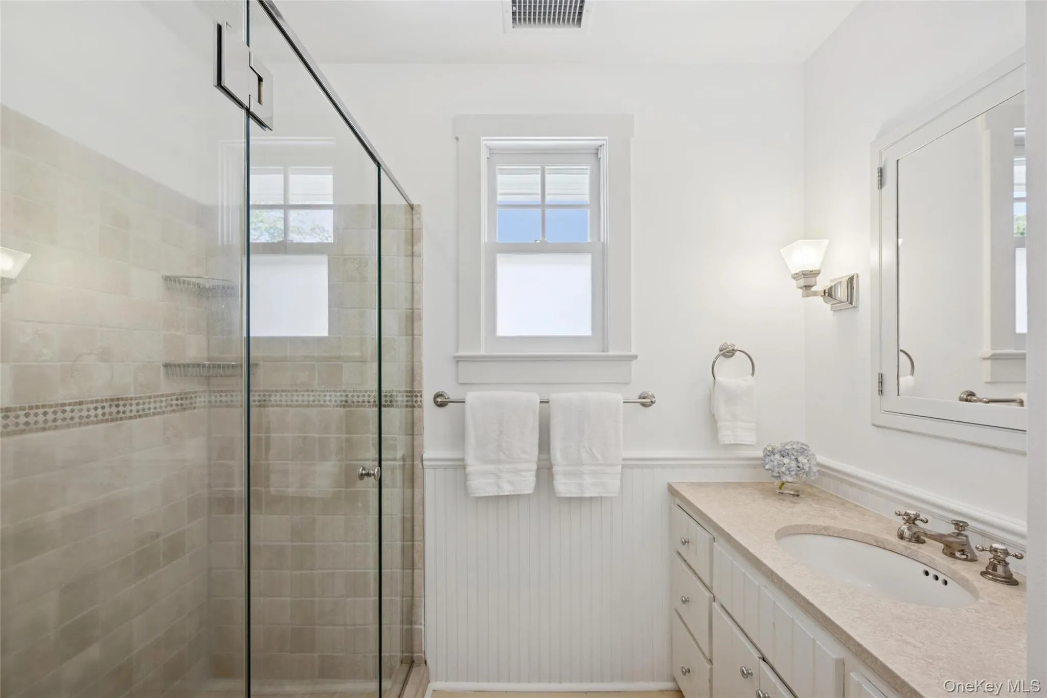 Bathroom with a shower stall, a wainscoted wall, and vanity Bathroom with a shower stall, a wainscoted wall, and vanity