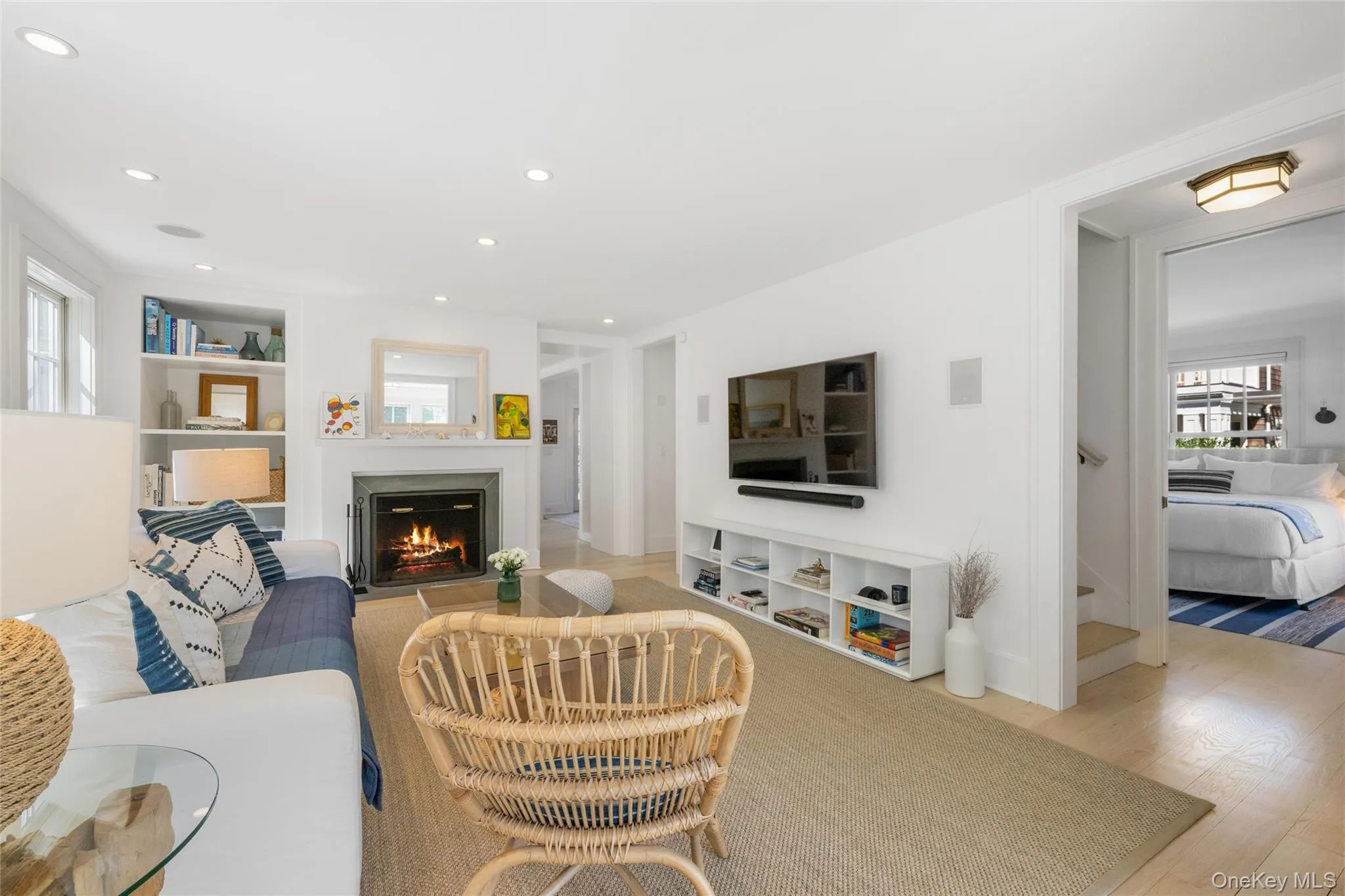 Living area with light wood-type flooring, a warm lit fireplace, stairway, recessed lighting, and built in shelves Living area with light wood-type flooring, a warm lit fireplace, stairway, recessed lighting, and built in shelves