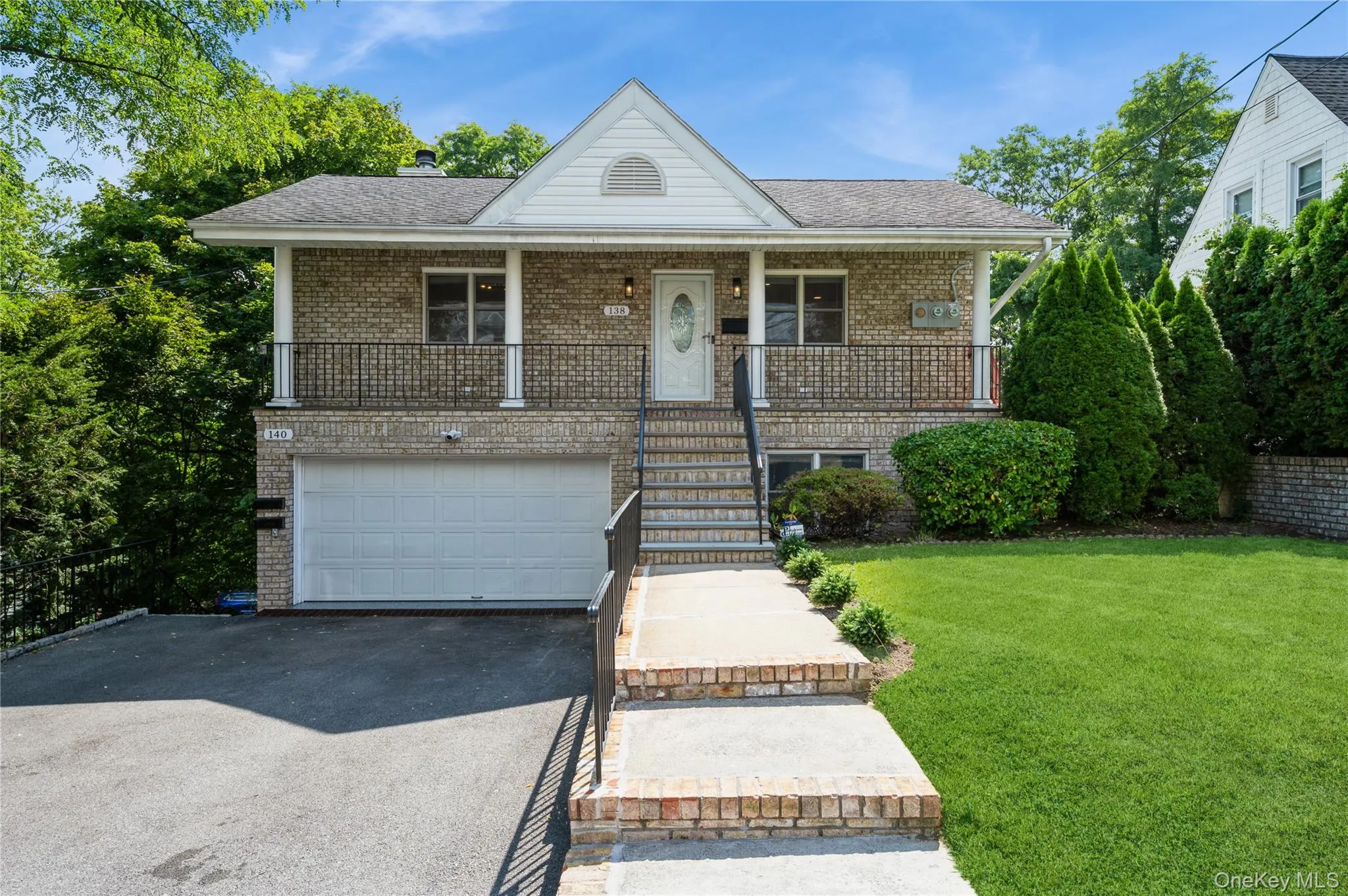 View of front of 138-140 Woodside Avenue duplex home featuring brick siding, covered porch, a private front yard, and shared driveway parking View of front of 138-140 Woodside Avenue duplex home featuring brick siding, covered porch, a private front yard, and shared driveway parking