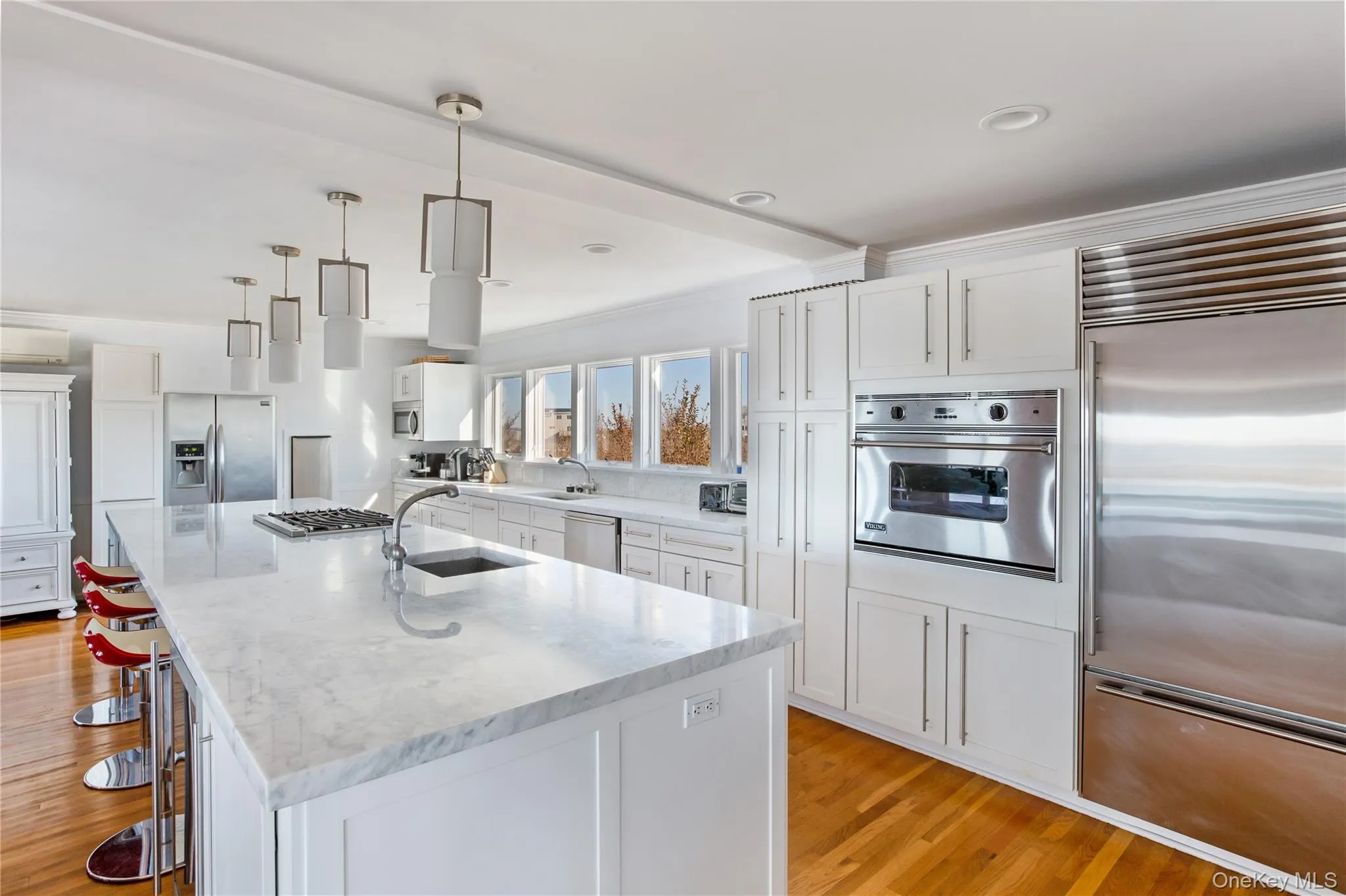 Kitchen with appliances with stainless steel finishes, white cabinets, hanging light fixtures, light wood-style flooring, and recessed lighting Kitchen with appliances with stainless steel finishes, white cabinets, hanging light fixtures, light wood-style flooring, and recessed lighting