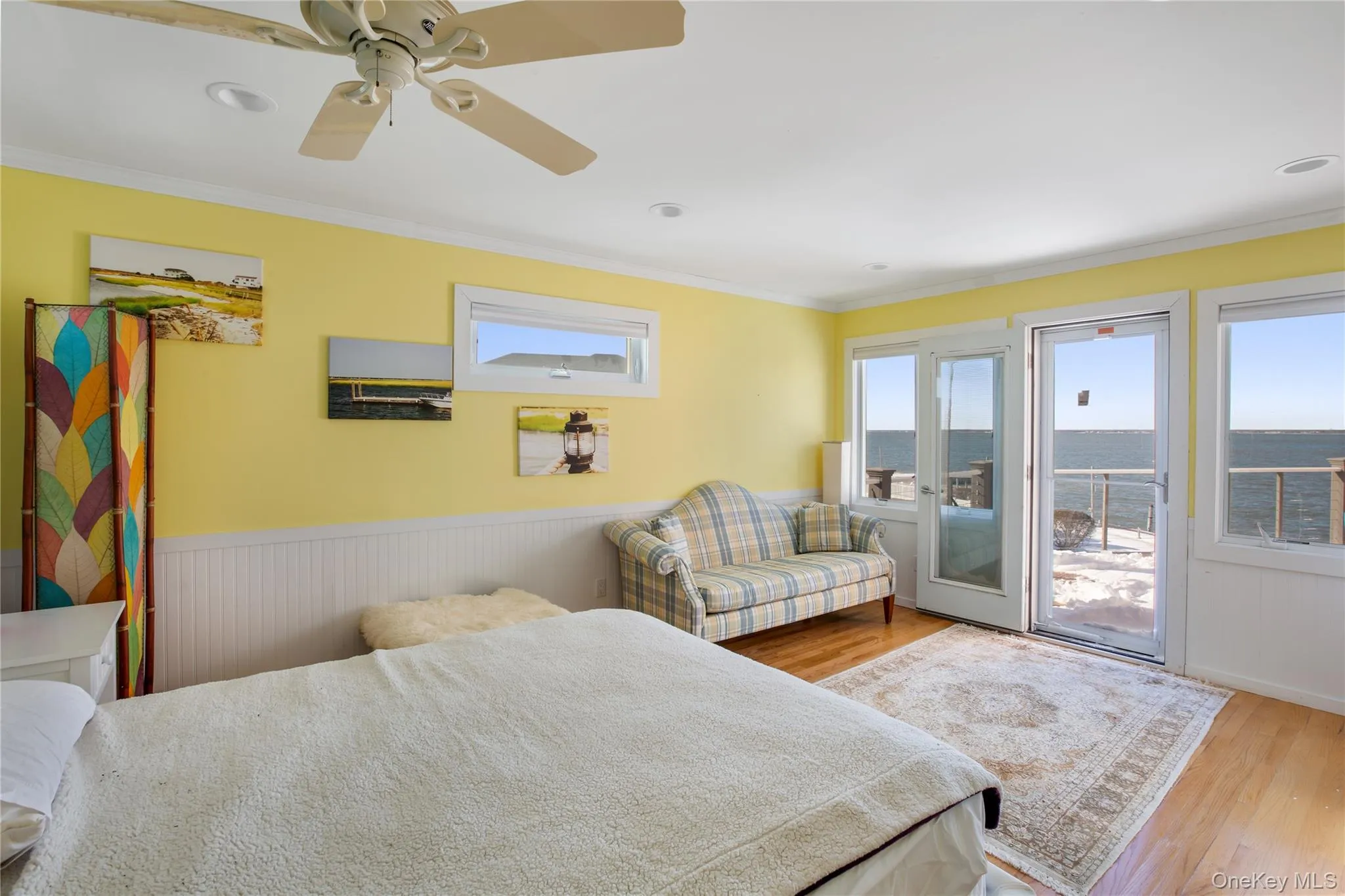 Bedroom with wood finished floors, multiple windows, access to outside, crown molding, and wainscoting Bedroom with wood finished floors, multiple windows, access to outside, crown molding, and wainscoting