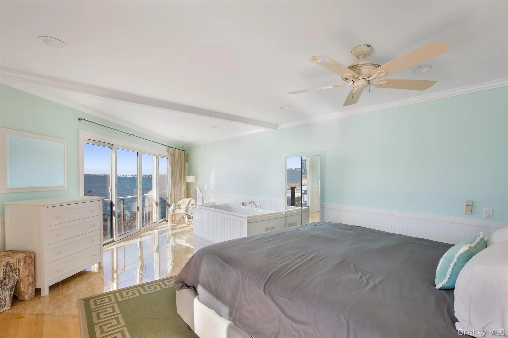 Bedroom featuring ornamental molding, a water view, ceiling fan, and wainscoting Bedroom featuring ornamental molding, a water view, ceiling fan, and wainscoting