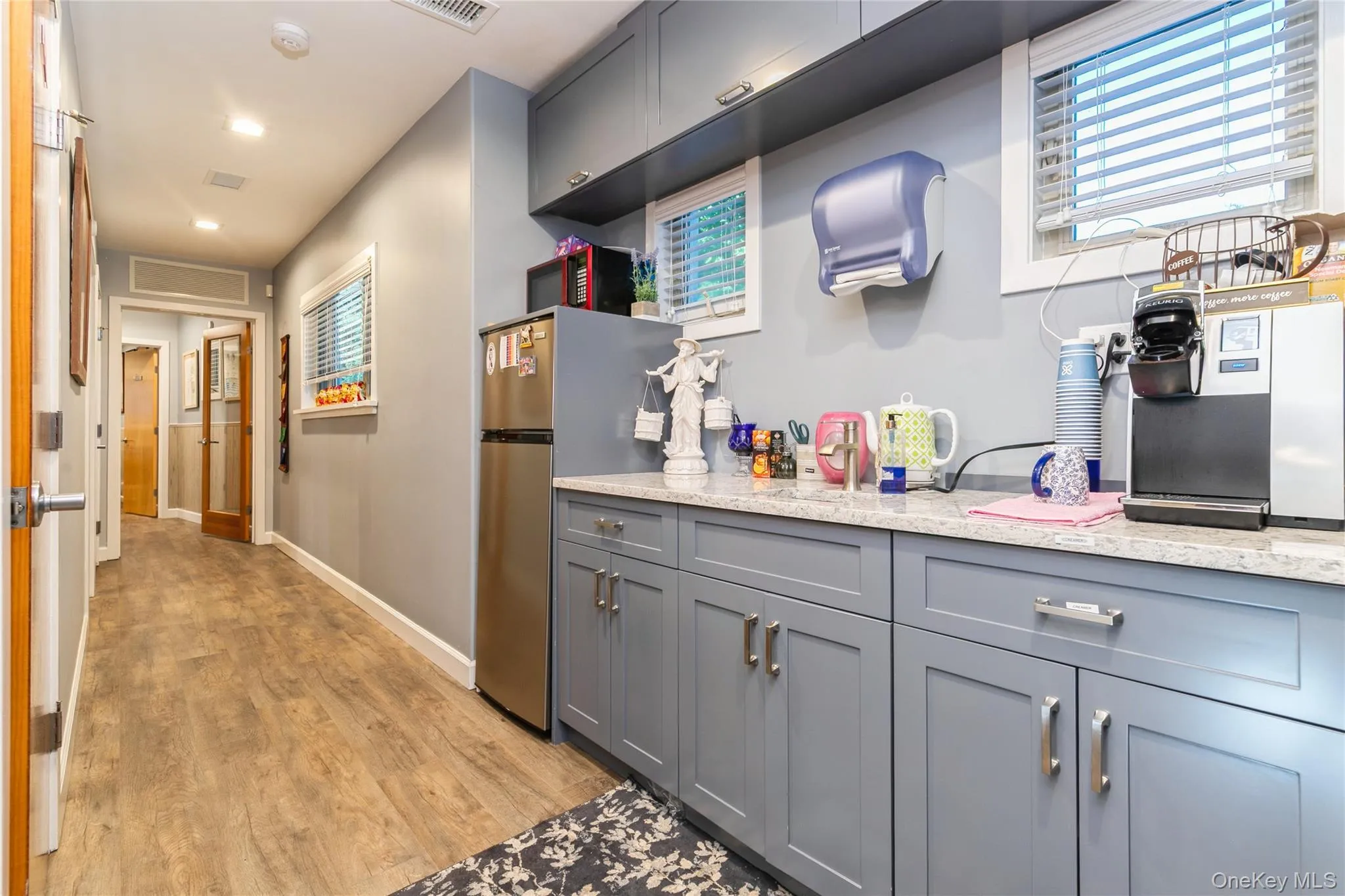 Kitchen featuring gray cabinets, light wood finished floors, light stone counters, freestanding refrigerator, and recessed lighting Kitchen featuring gray cabinets, light wood finished floors, light stone counters, freestanding refrigerator, and recessed lighting