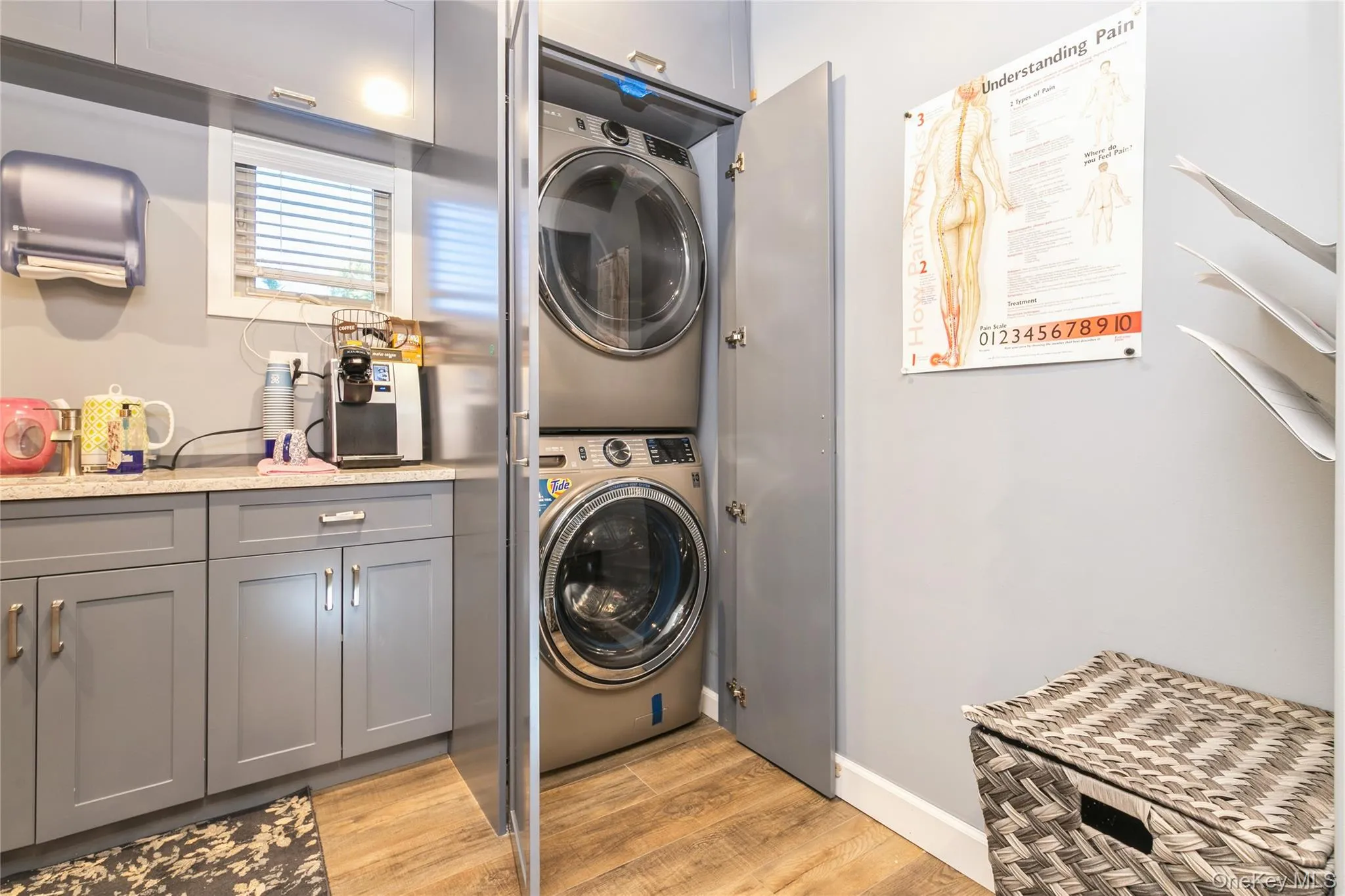 Laundry area with light wood-style floors and stacked washer and clothes dryer Laundry area with light wood-style floors and stacked washer and clothes dryer