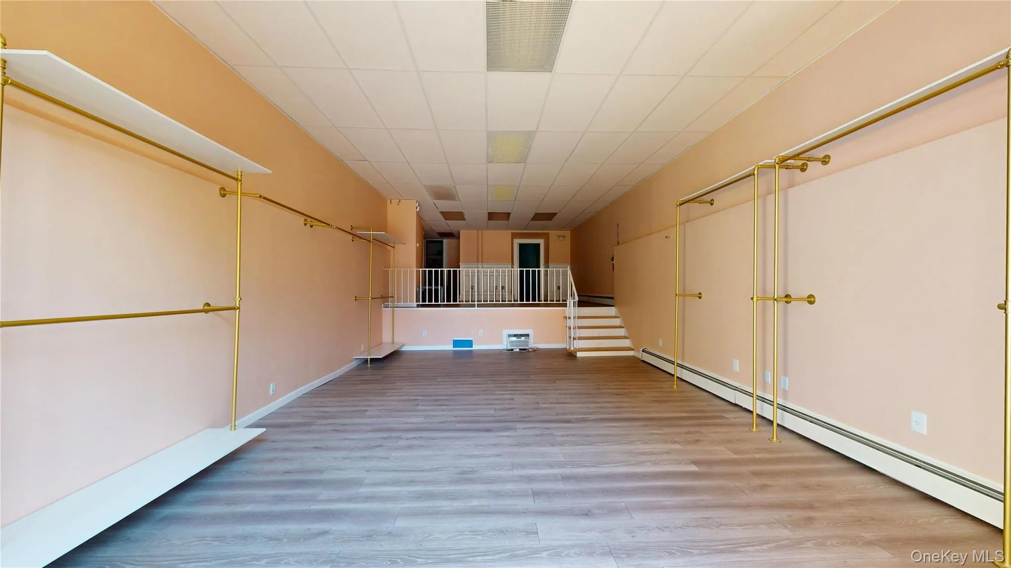 Below grade area with a baseboard heating unit, light wood finished floors, and stairs Below grade area with a baseboard heating unit, light wood finished floors, and stairs