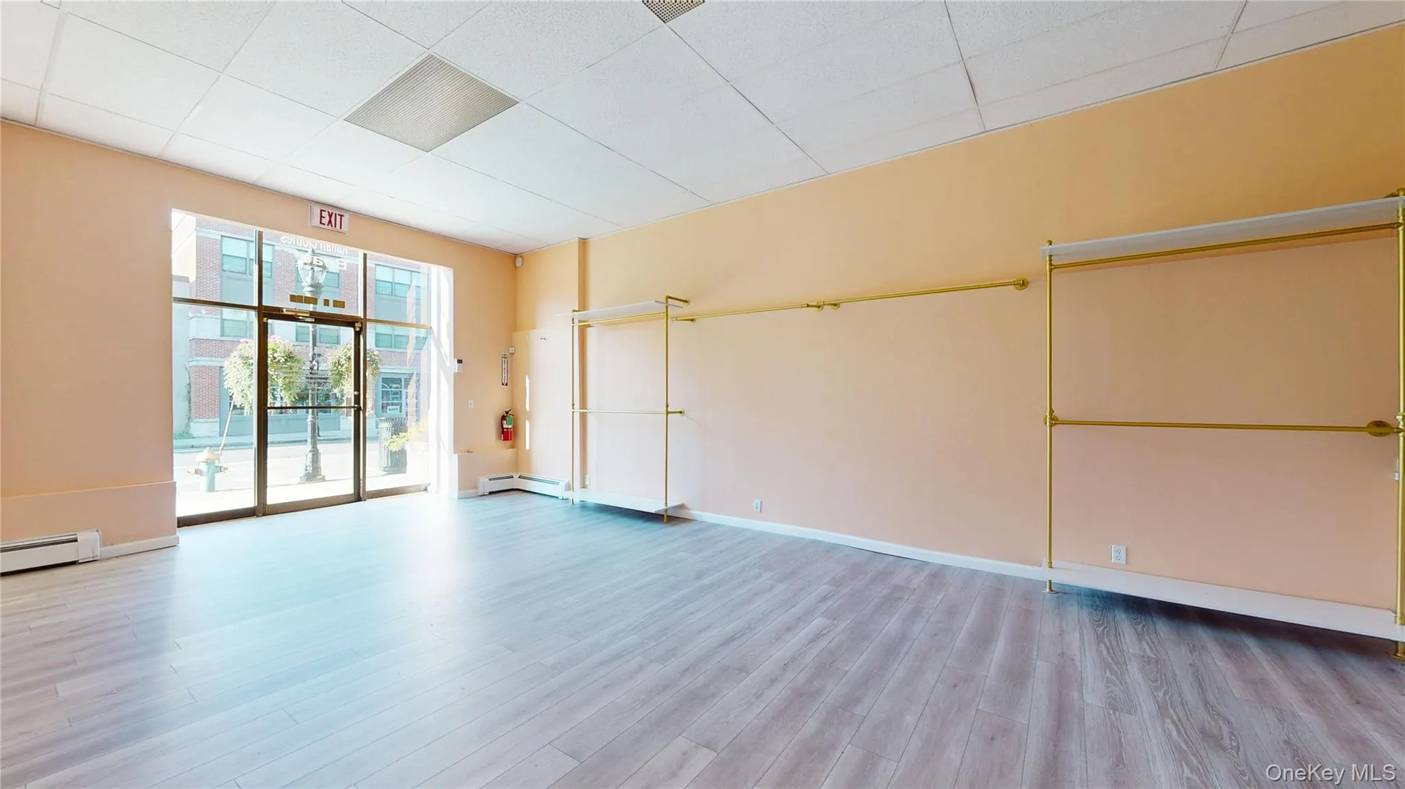 Unfurnished room with light wood finished floors, a drop ceiling, and baseboard heating Unfurnished room with light wood finished floors, a drop ceiling, and baseboard heating